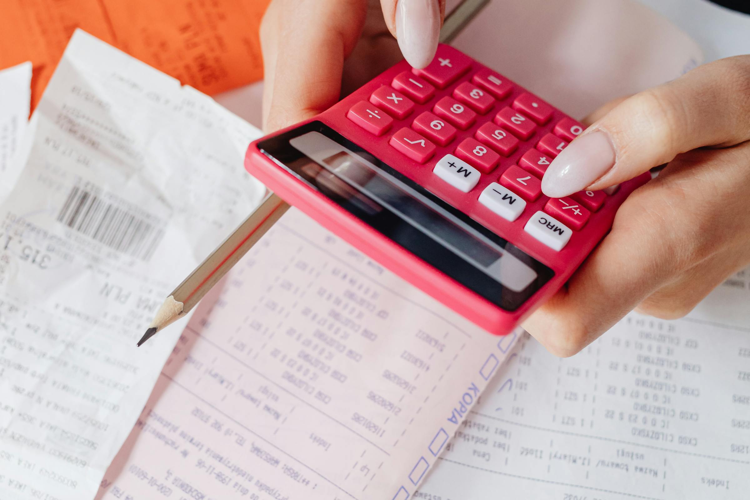 A woman using a calculator while dealing with bills | Source: Pexels