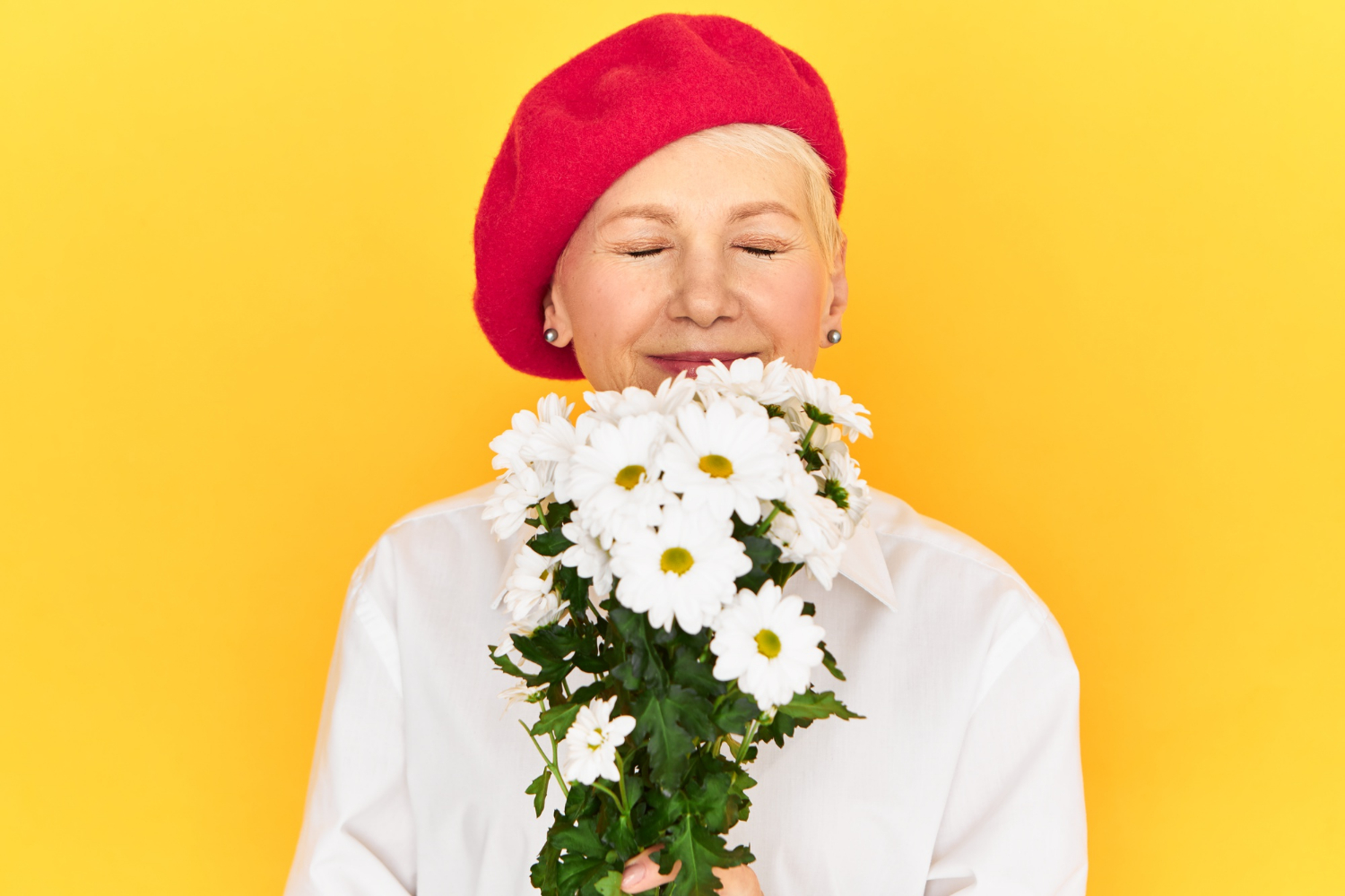 A senior woman holding a bouquet of white daisies | Source: Freepik