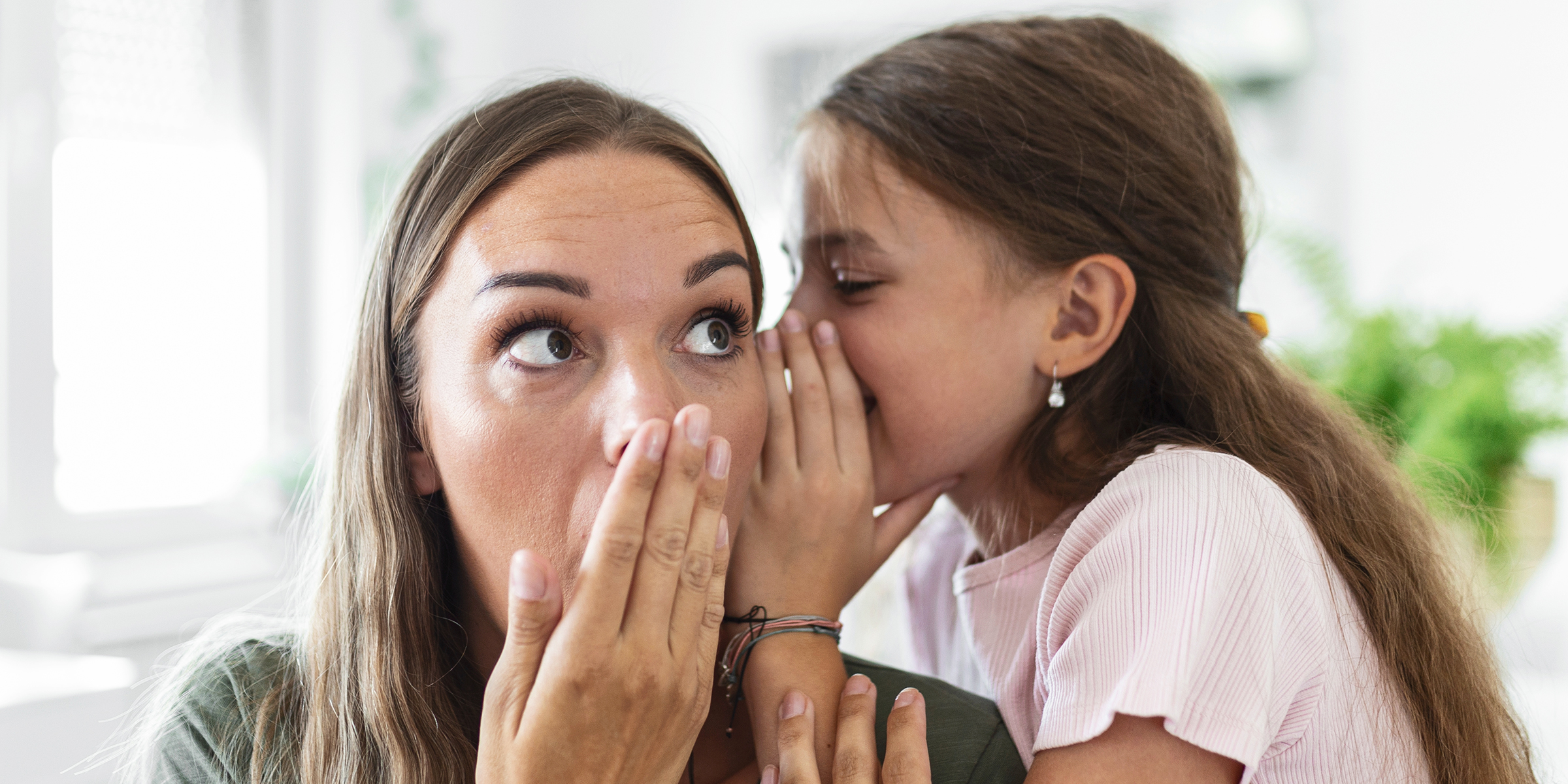 A girl whispering in her mother's ear | Source: Shutterstock