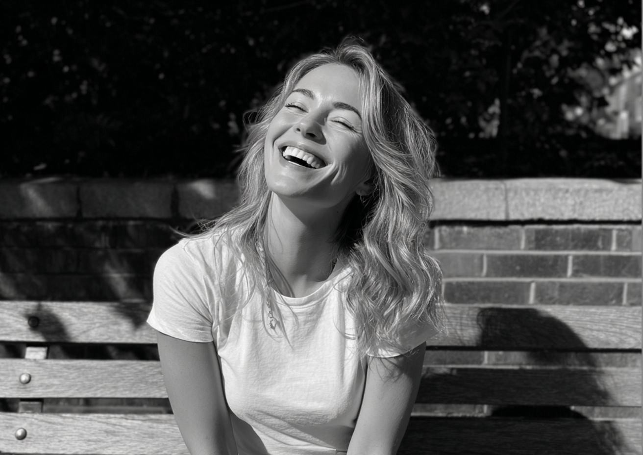 A laughing woman sitting on a bench | Source: Midjourney