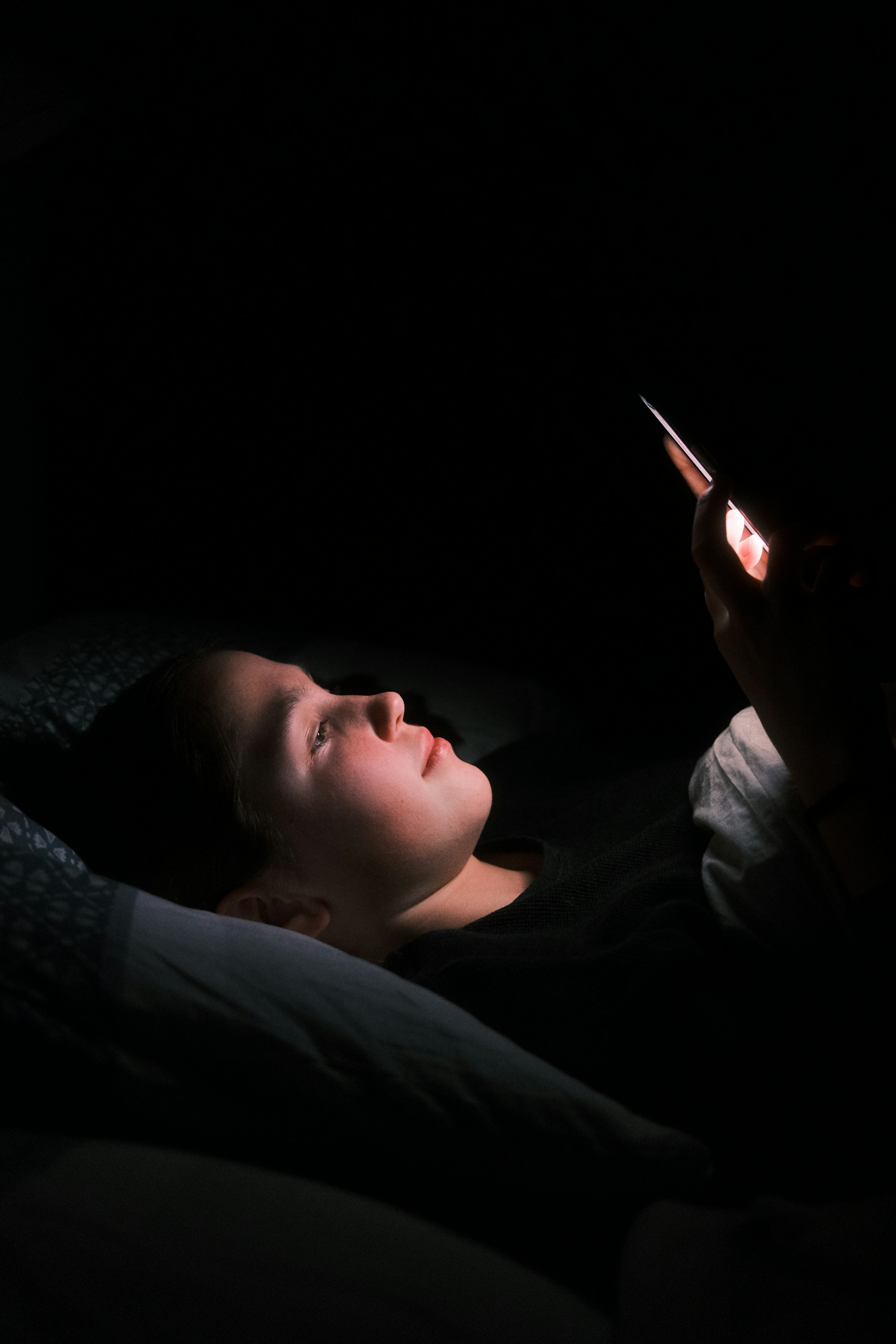 A woman using her phone in bed at night | Source: Unsplash