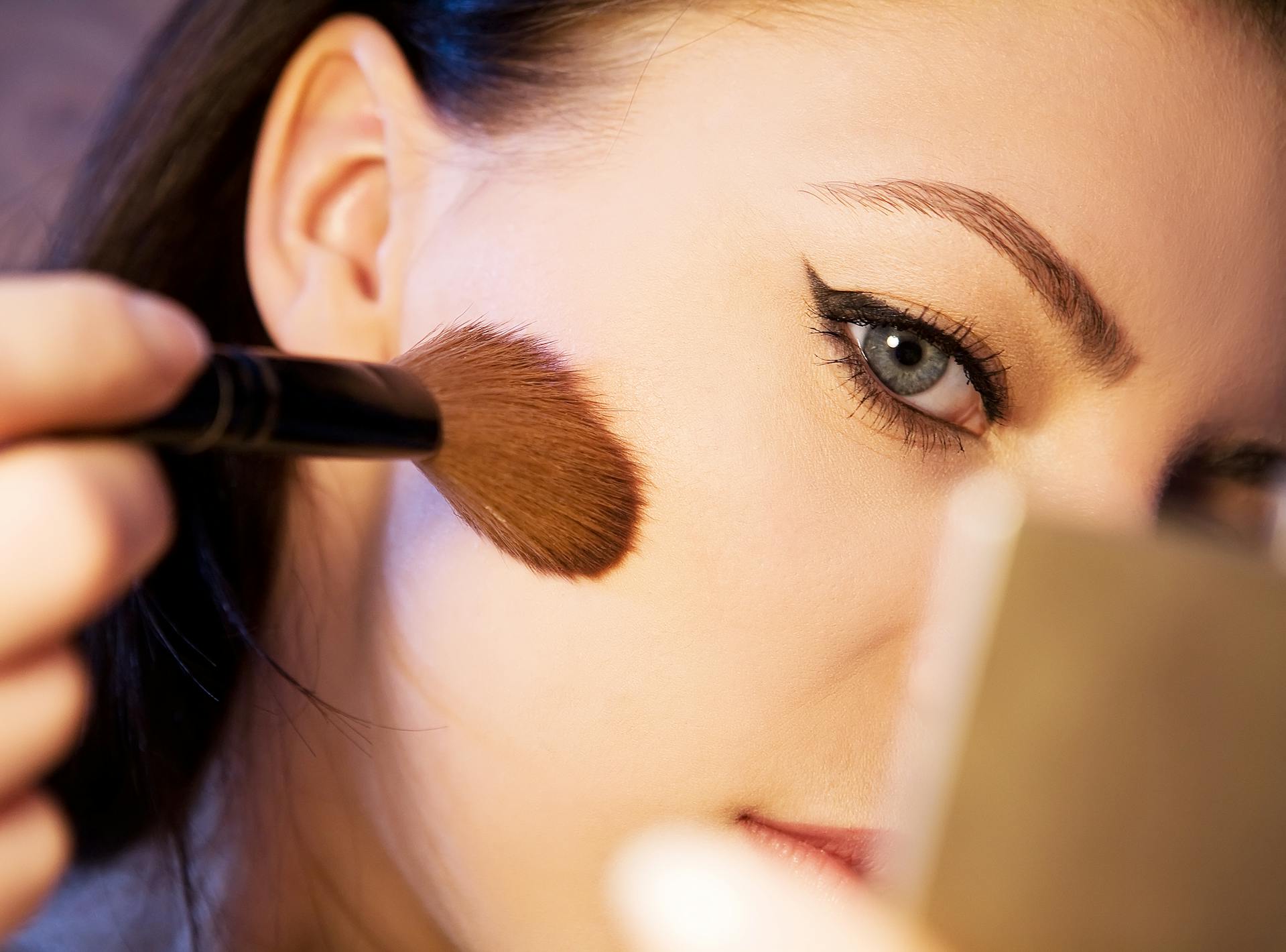 A woman adding final touches to her face using a makeup brush | Source: Pexels