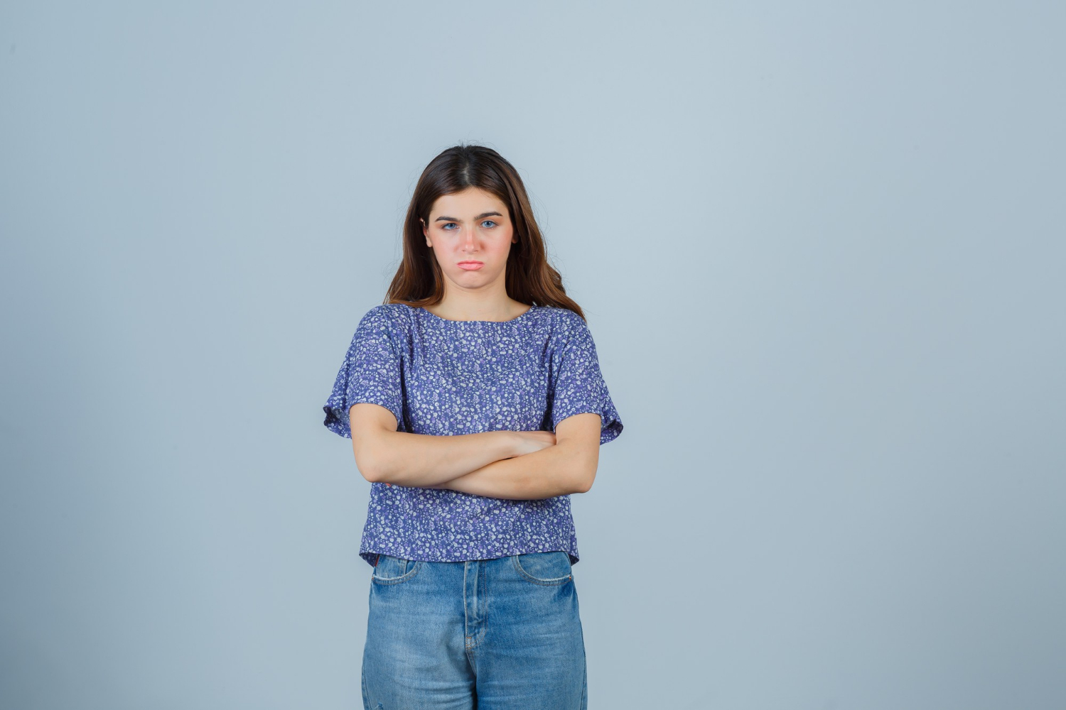 A frustrated young woman with her arms crossed | Source: Freepik