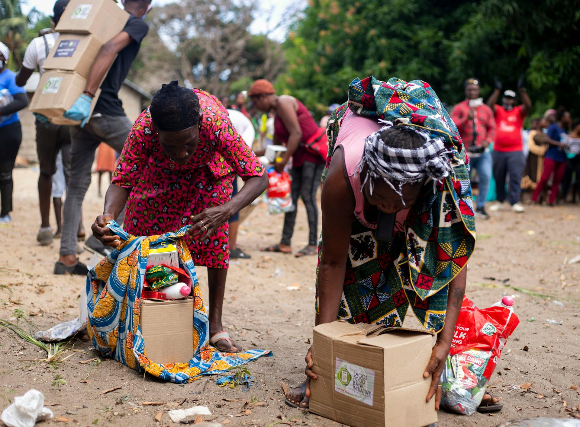 People picking up supplies packed in a cardboard box | Source: Pexels