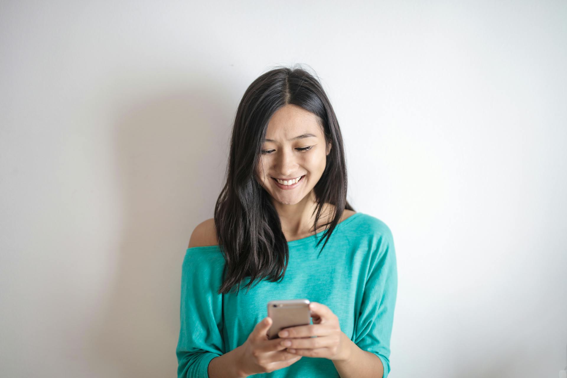 A woman smiling down at her phone | Source: Pexels