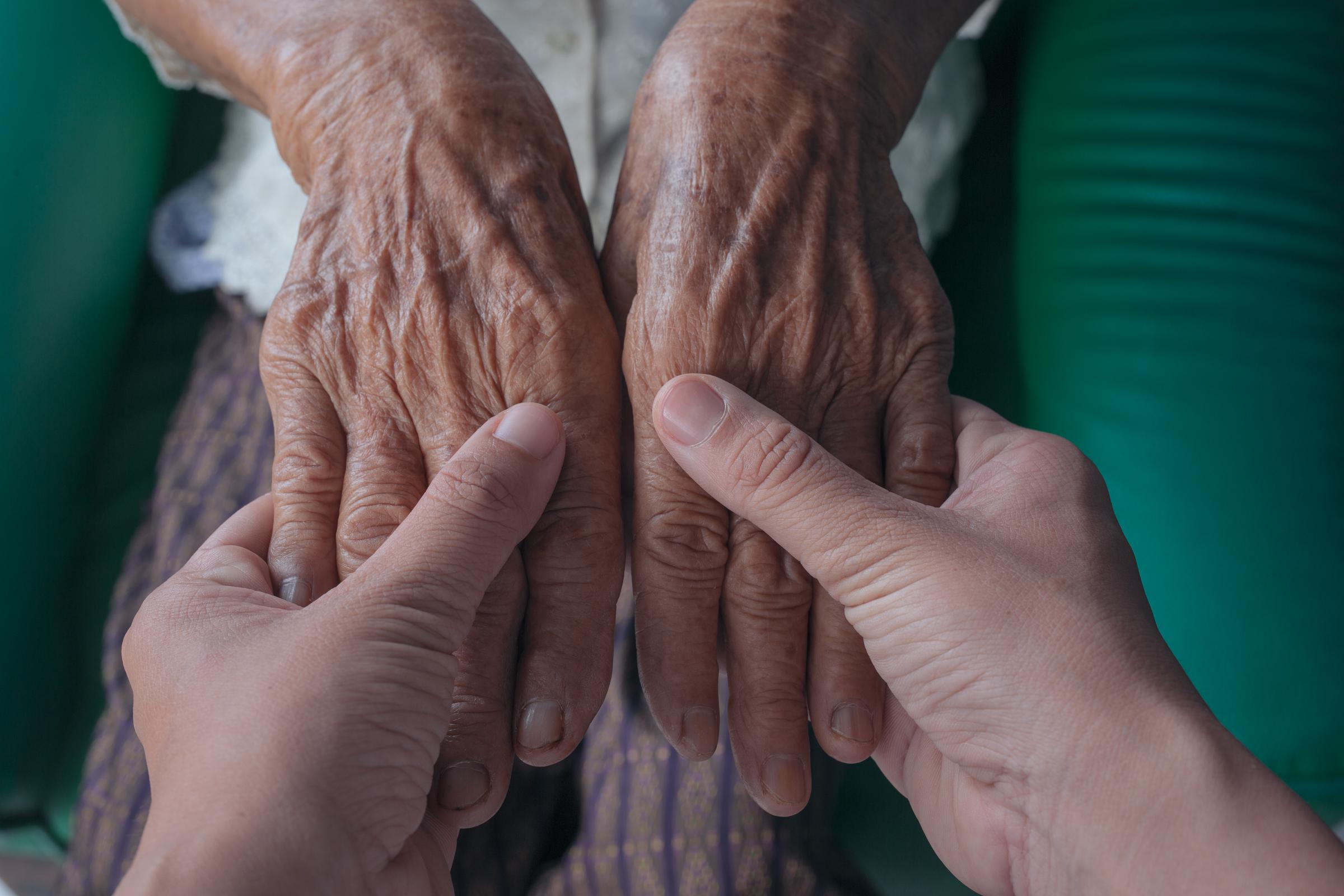 Close-up shot of a young man holding his grandmother's hand | Source: Freepik