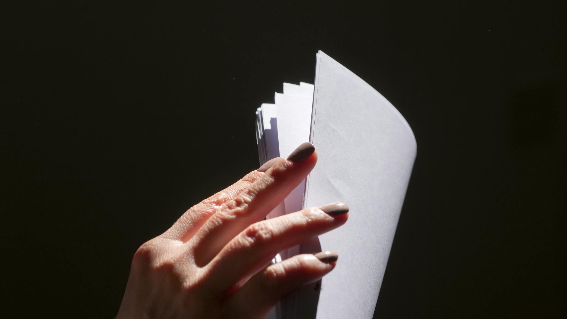 Close-up shot of a woman flipping through sheets of paper | Source: Pexels