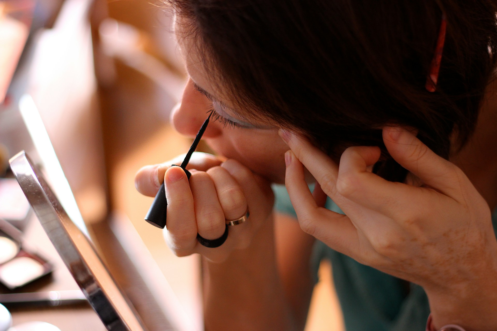 A woman looking in the mirror and applying eyeliner | Source: Unsplash