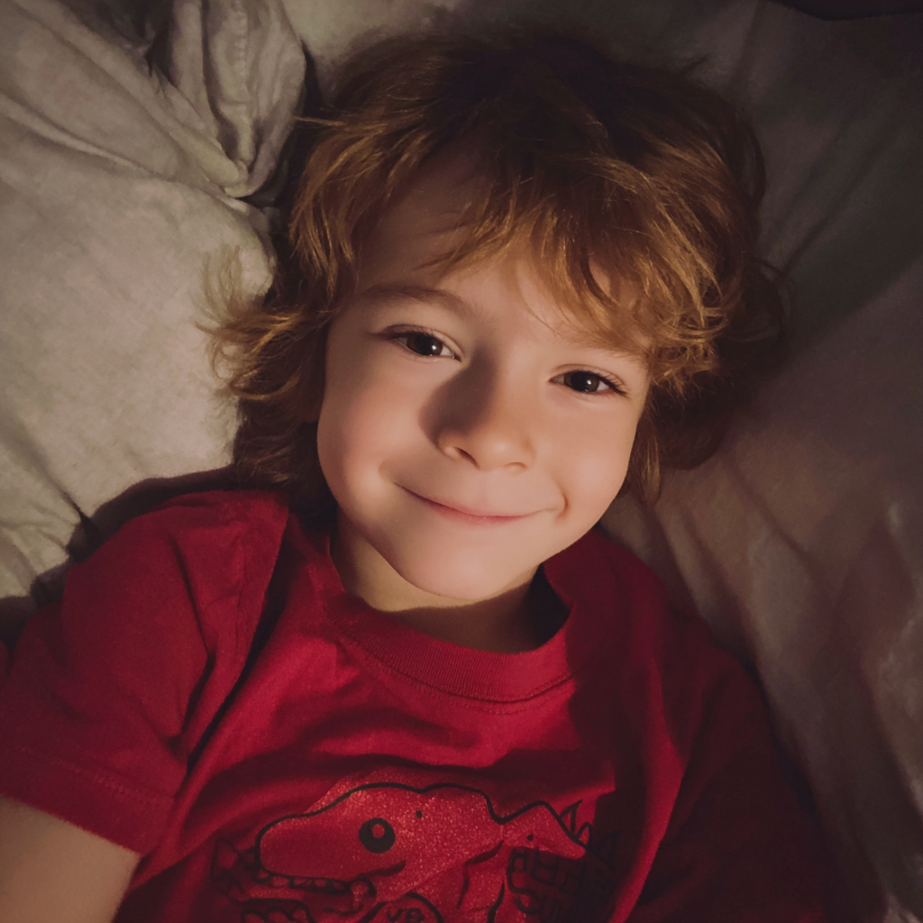 A little boy lying in his bed | Source: Midjourney