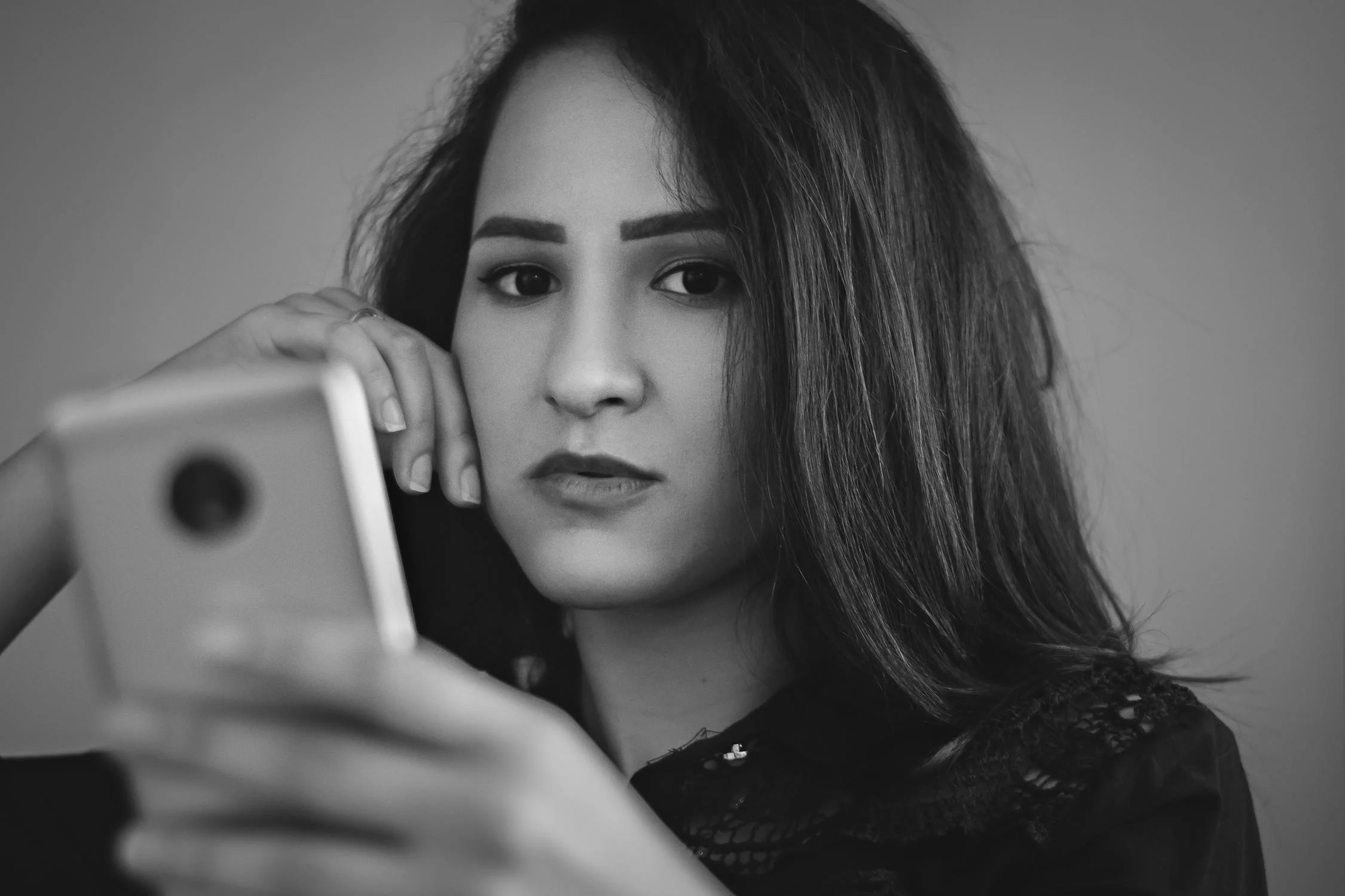 Une femme sérieuse avec un téléphone dans les mains | Source : Pexels