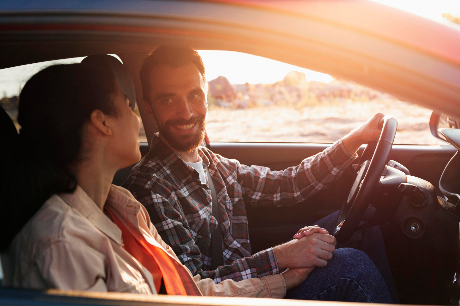 A delighted man looking at his partner and smiling in their car | Source: Freepik