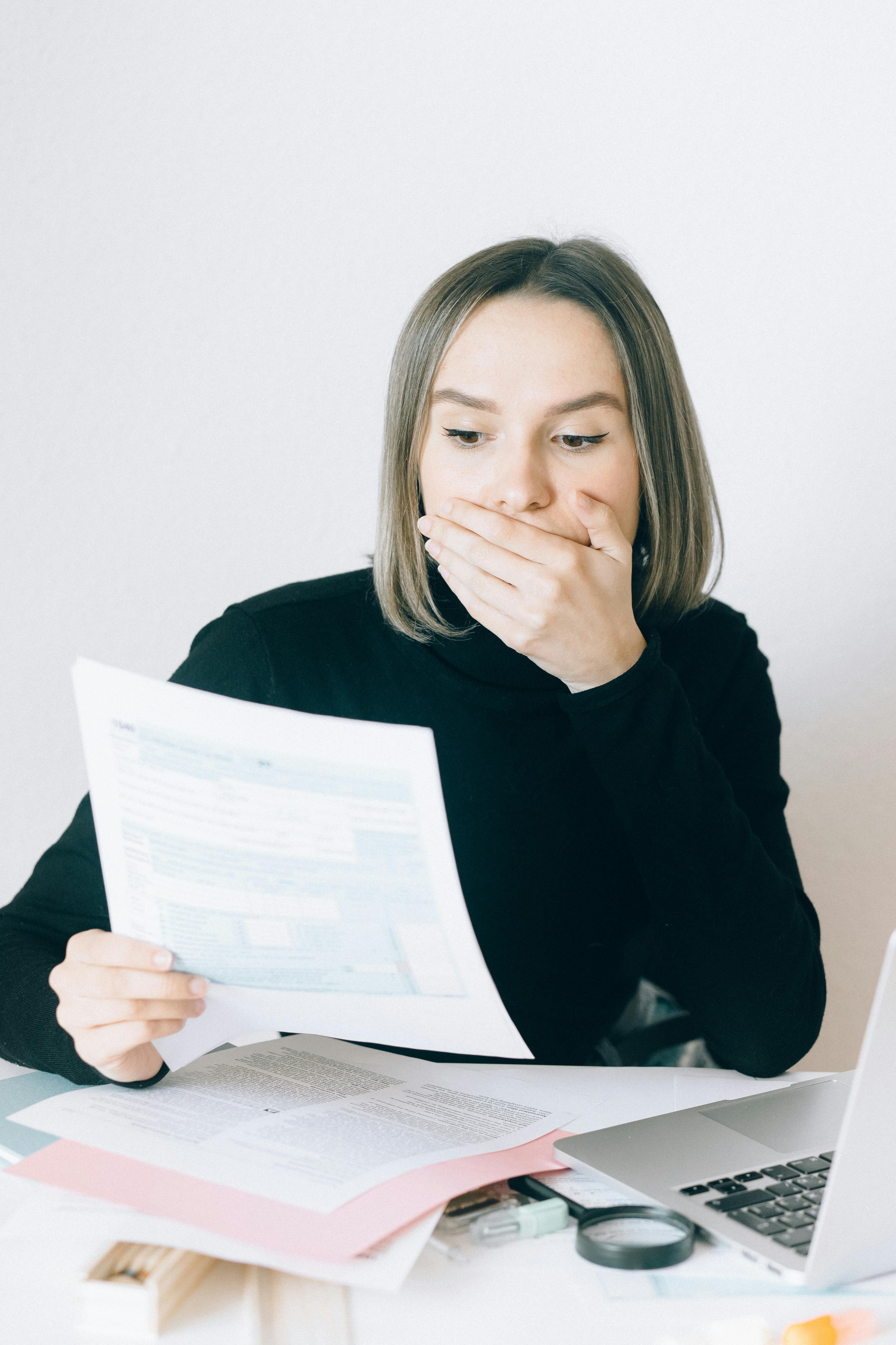 Una mujer sorprendida sosteniendo un documento | Fuente: Pexels