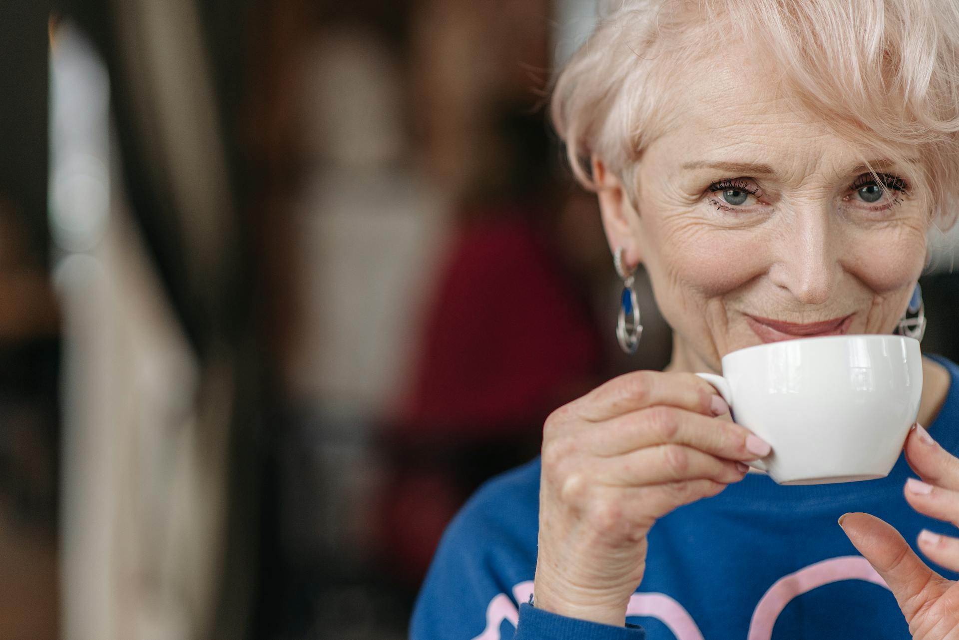 A senior woman smiling while holding a cup of coffee | Source: Pexels