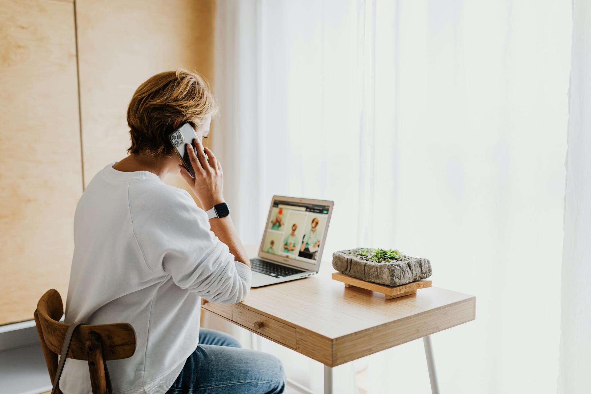 A woman talking on her phone while using laptop | Source: Pexels