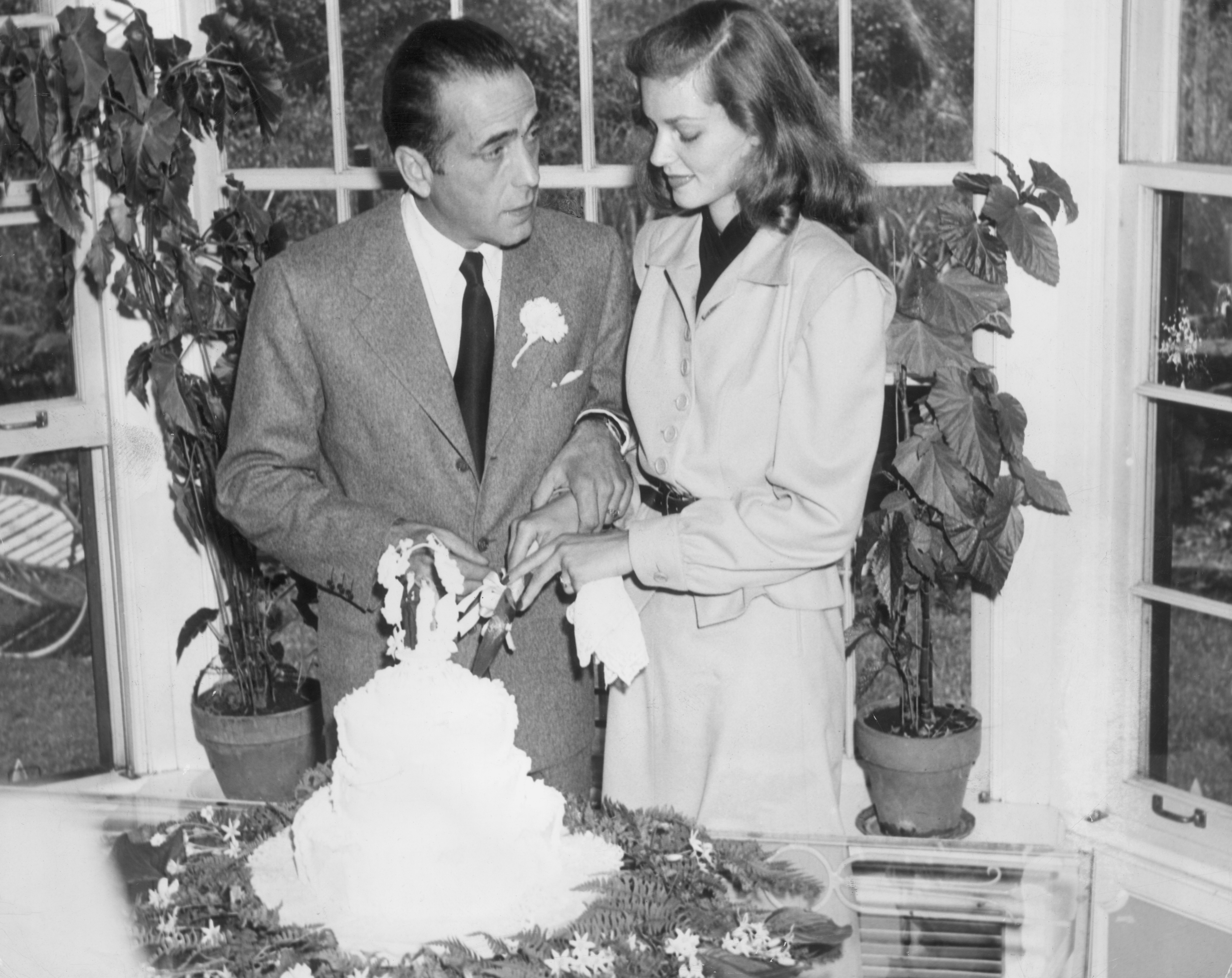 Humphrey Bogart and Lauren Bacall cut the cake at their wedding on May 21, 1945. | Source: Source: Getty Images