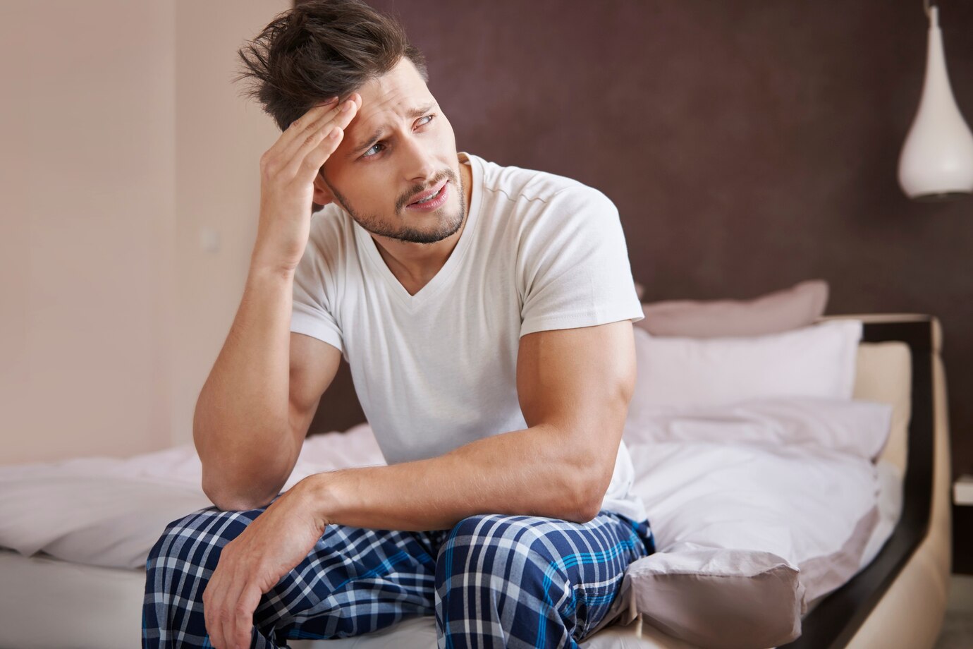 A tired puzzled man sitting on his bed | Source: Freepik