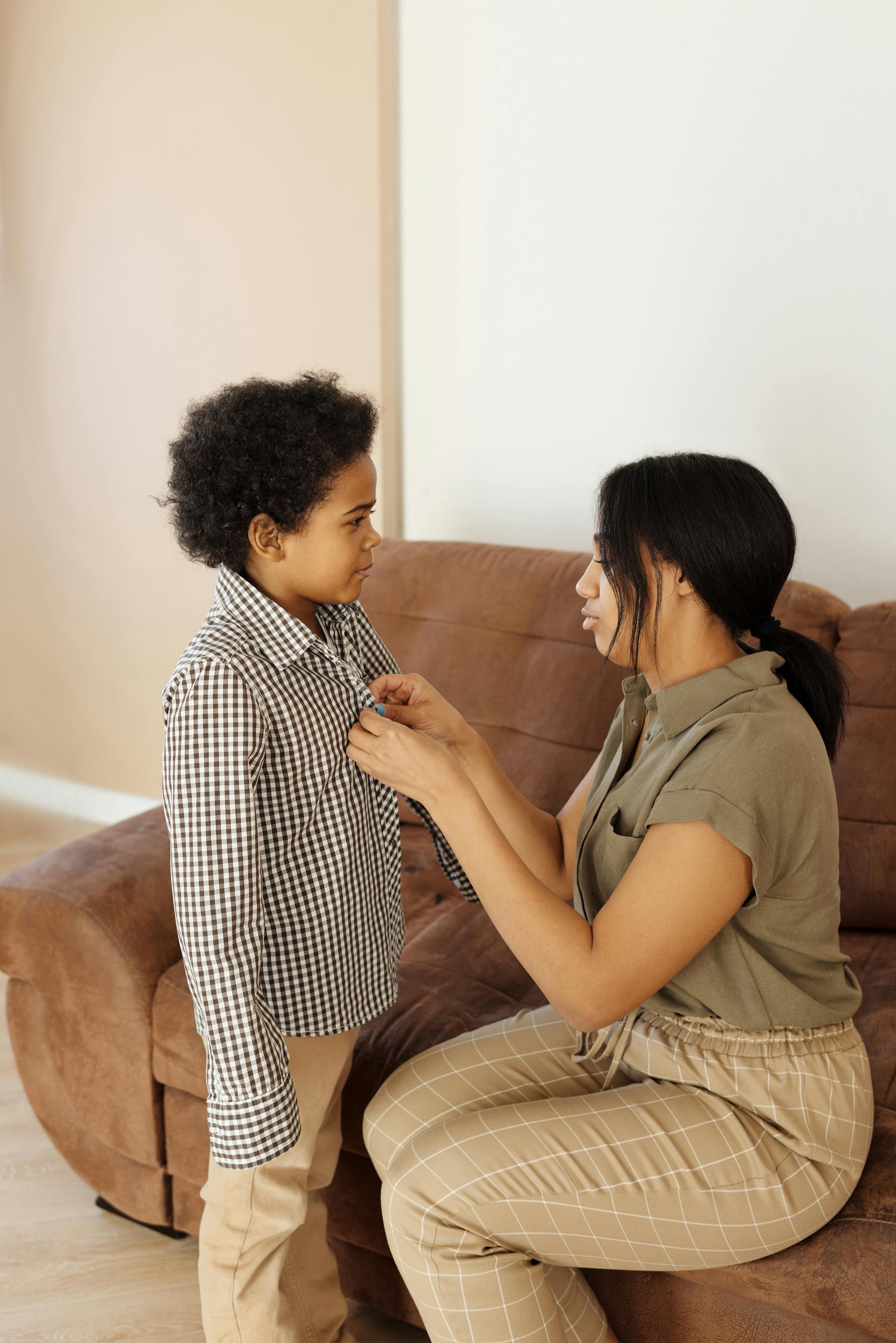 A mother helps her son get dressed | Source: Pexels