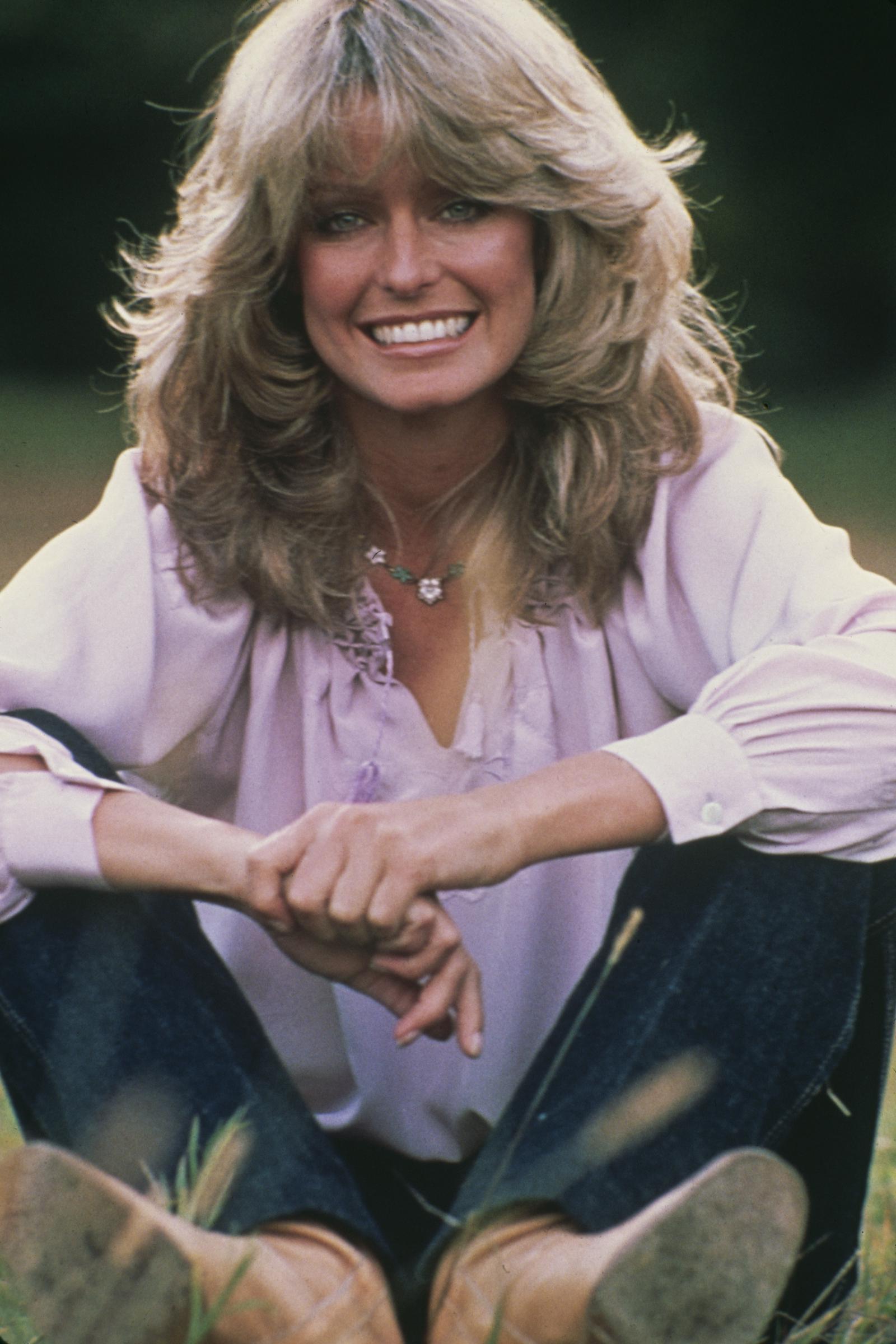 Farrah Fawcett-Majors smiles while sitting on the grass in February 1978. | Source: Getty Images