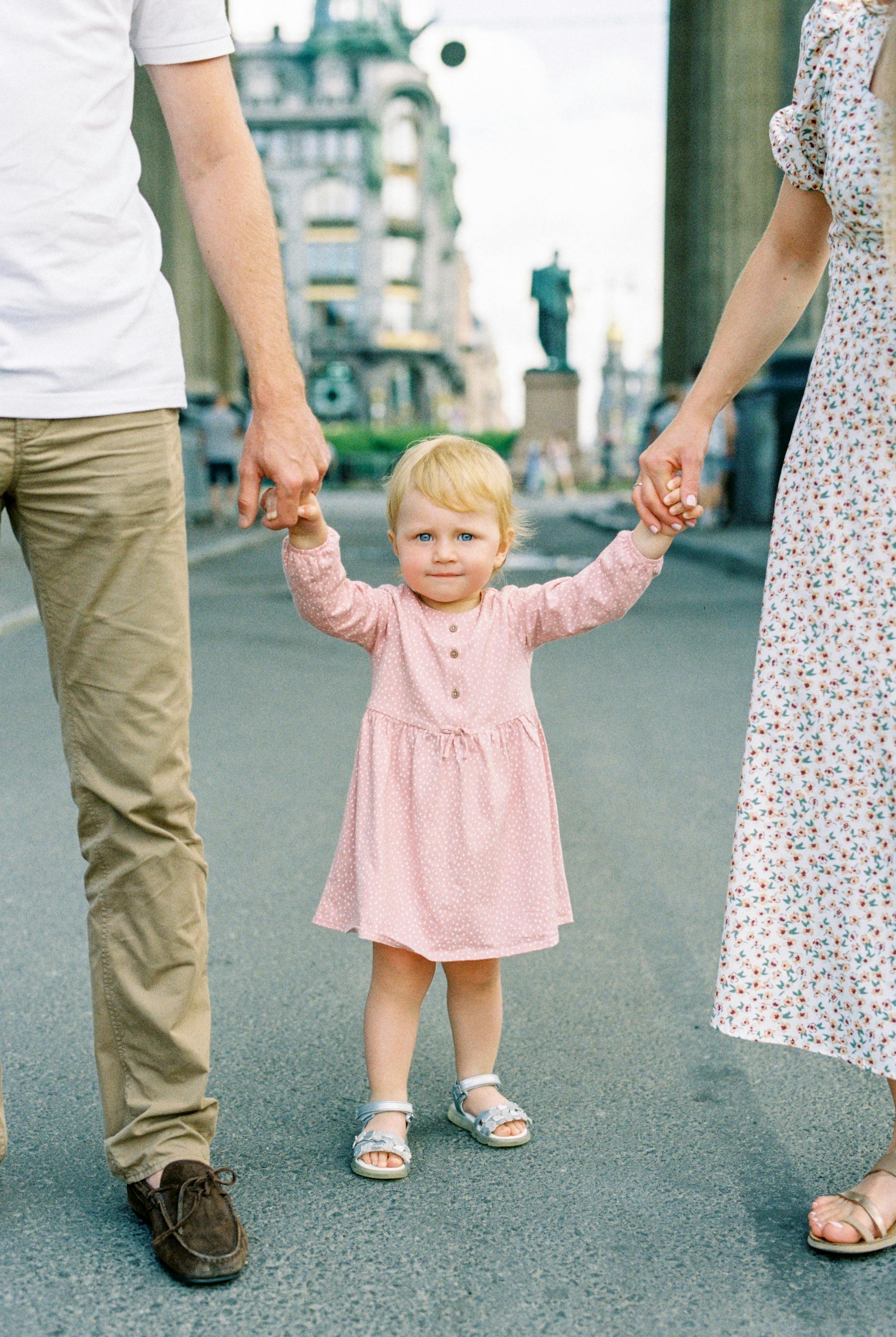 A little girl holding her parents' hands | Source: Pexels