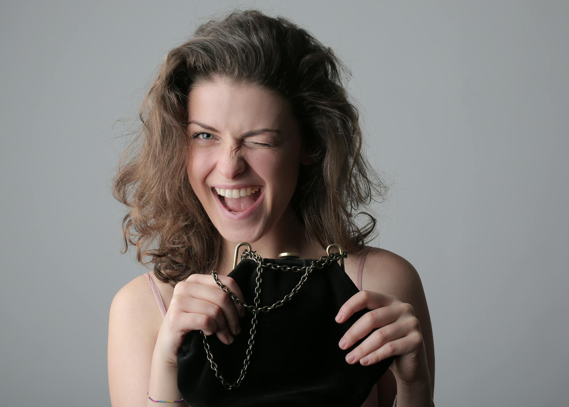 A woman holding her purse winking | Source: Pexels
