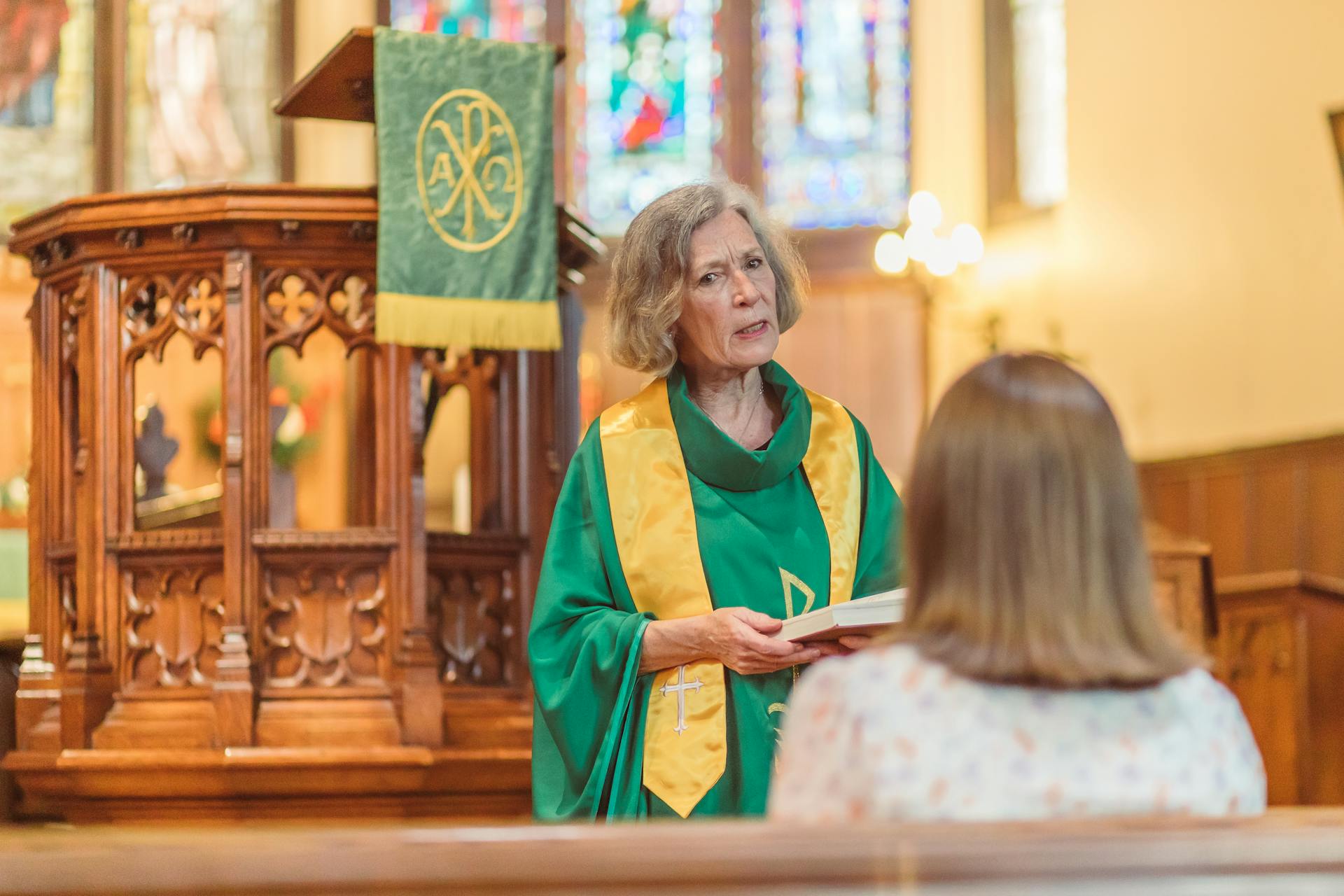 An older woman holding a book and talking to a young woman in the church | Source: Pexels