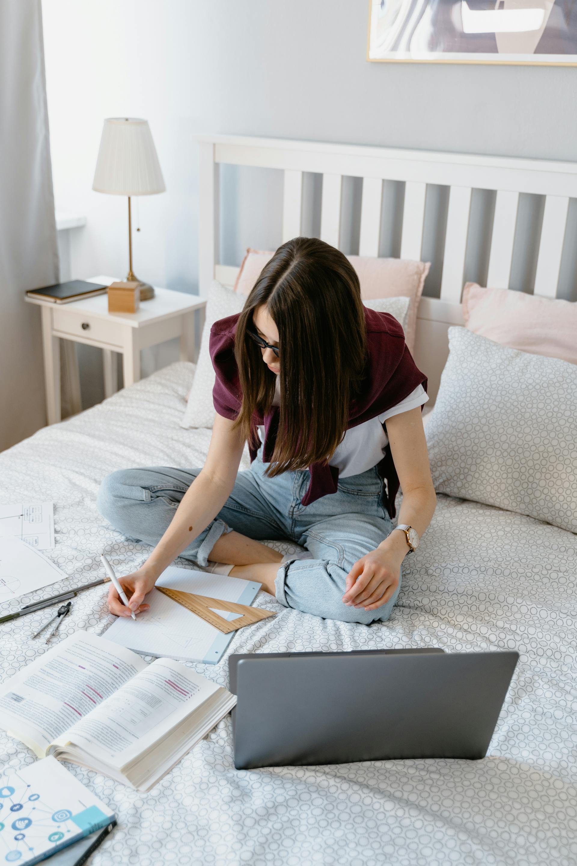 Uma mulher estudando sentada na cama | Fonte: Pexels