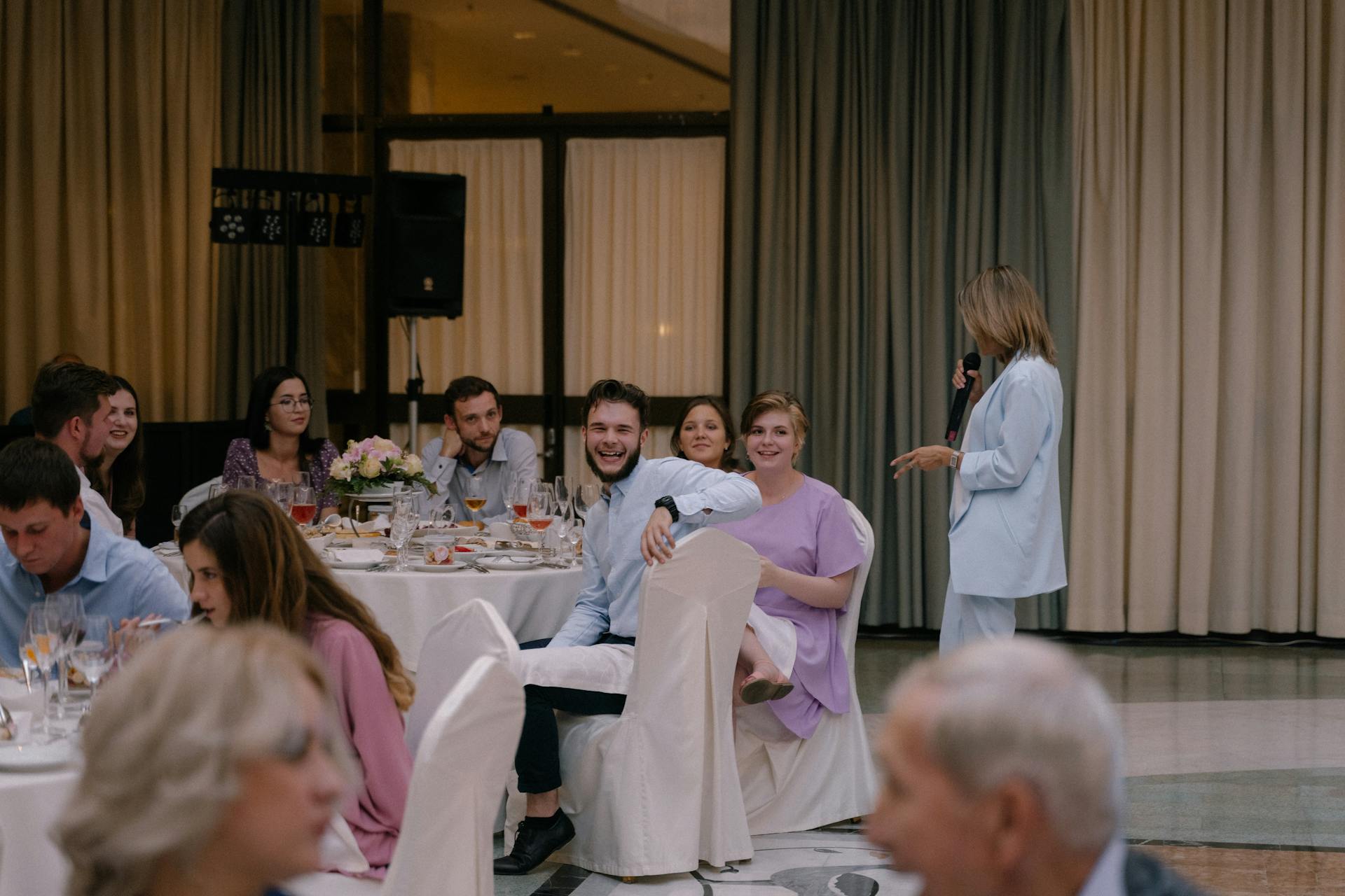 Guests seen laughing while a woman is delivering a speech on the mic | Source: Pexels