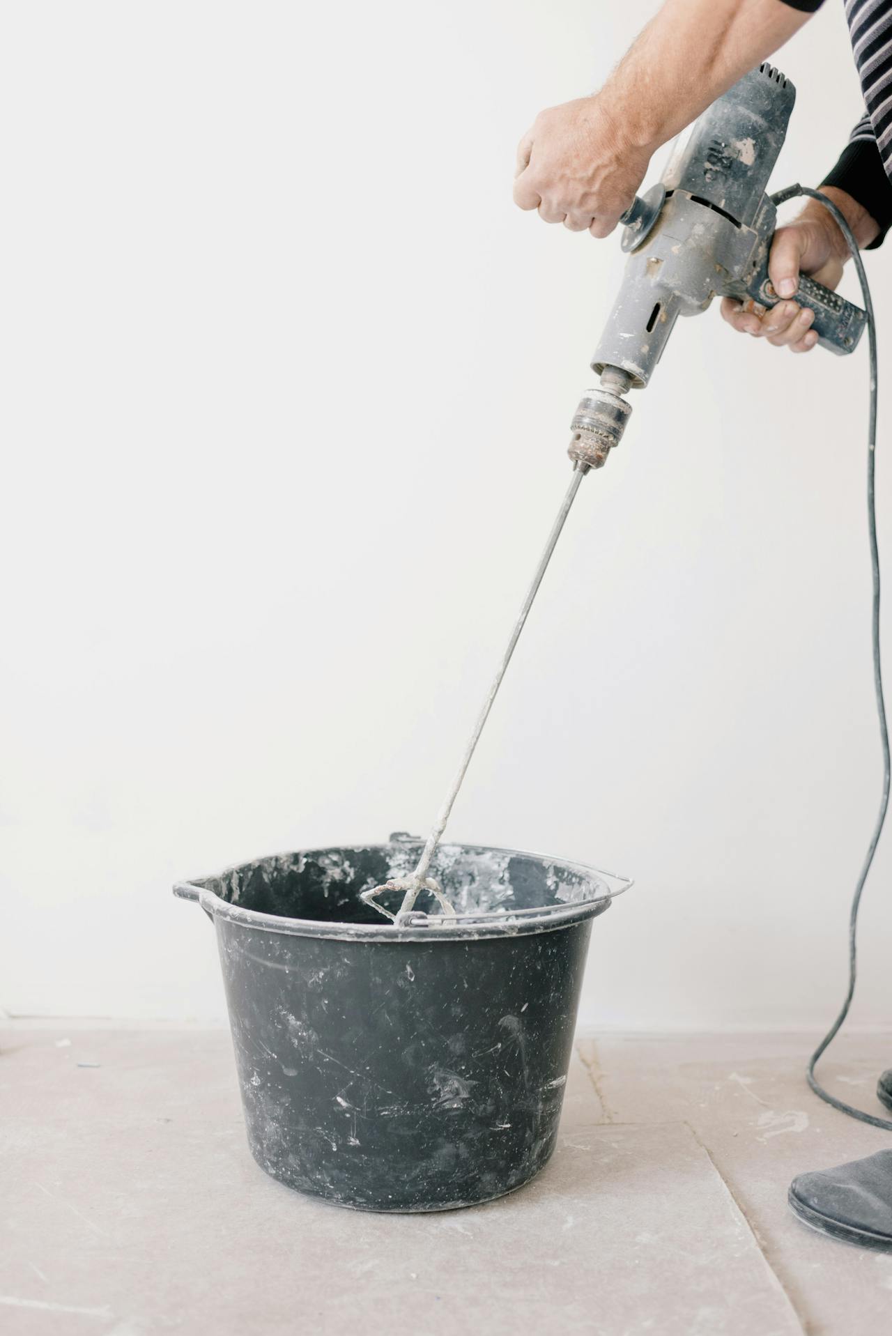 Cropped shot of a man mixing cement in a bucket | Source: Pexels