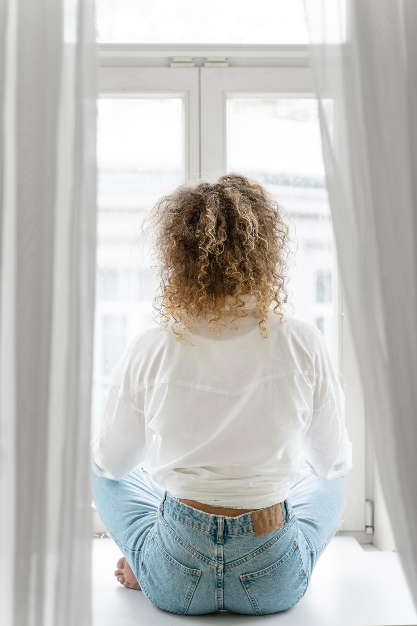 A woman sitting looking through a window | Source: Freepik