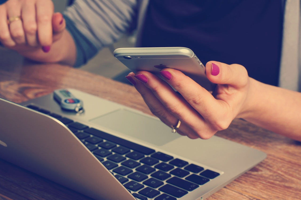 A closeup of a woman working on her laptop while using her phone | Source: Pixabay