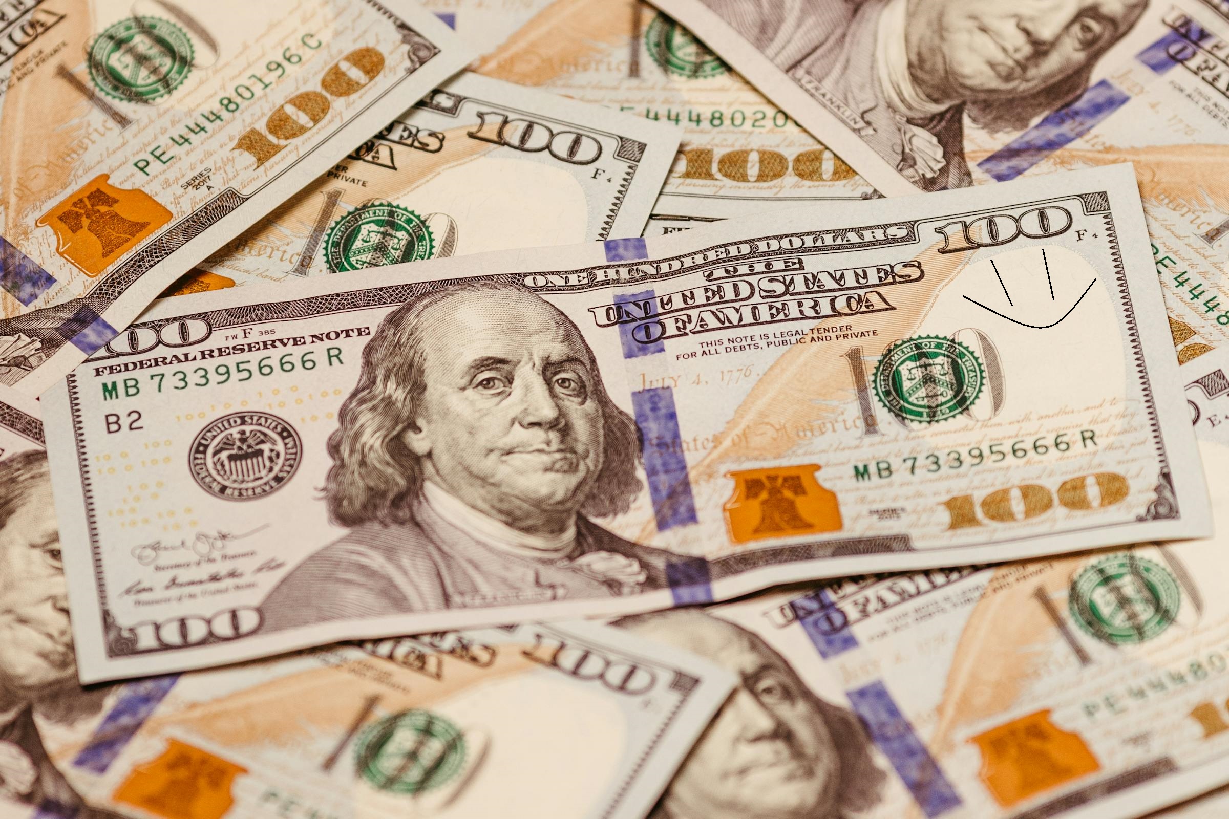 A stack of cash with a $100 bill on top, featuring a smiley face | Source: Pexels