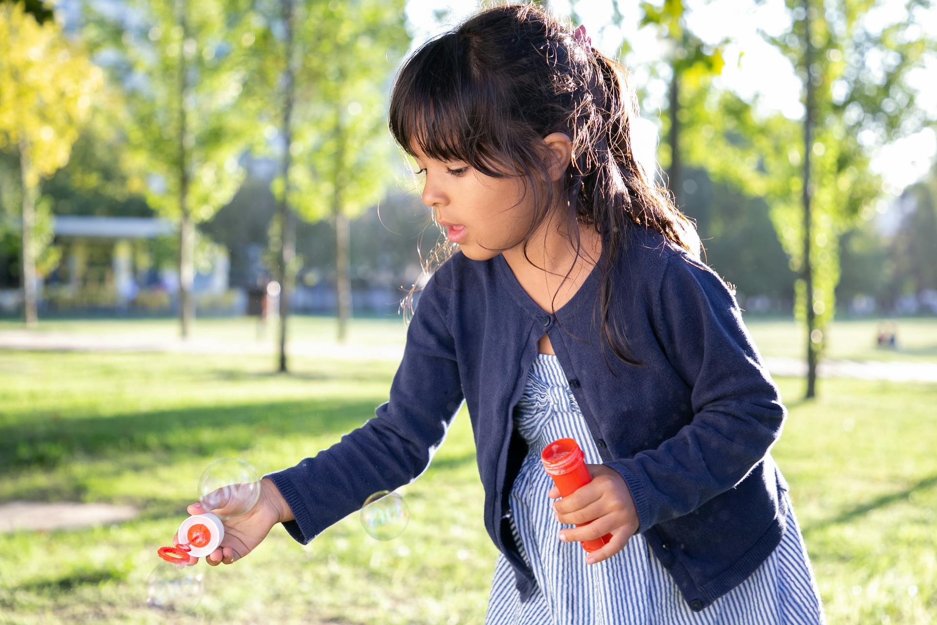 A girl blowing bubbles in a park | Source: Pexels