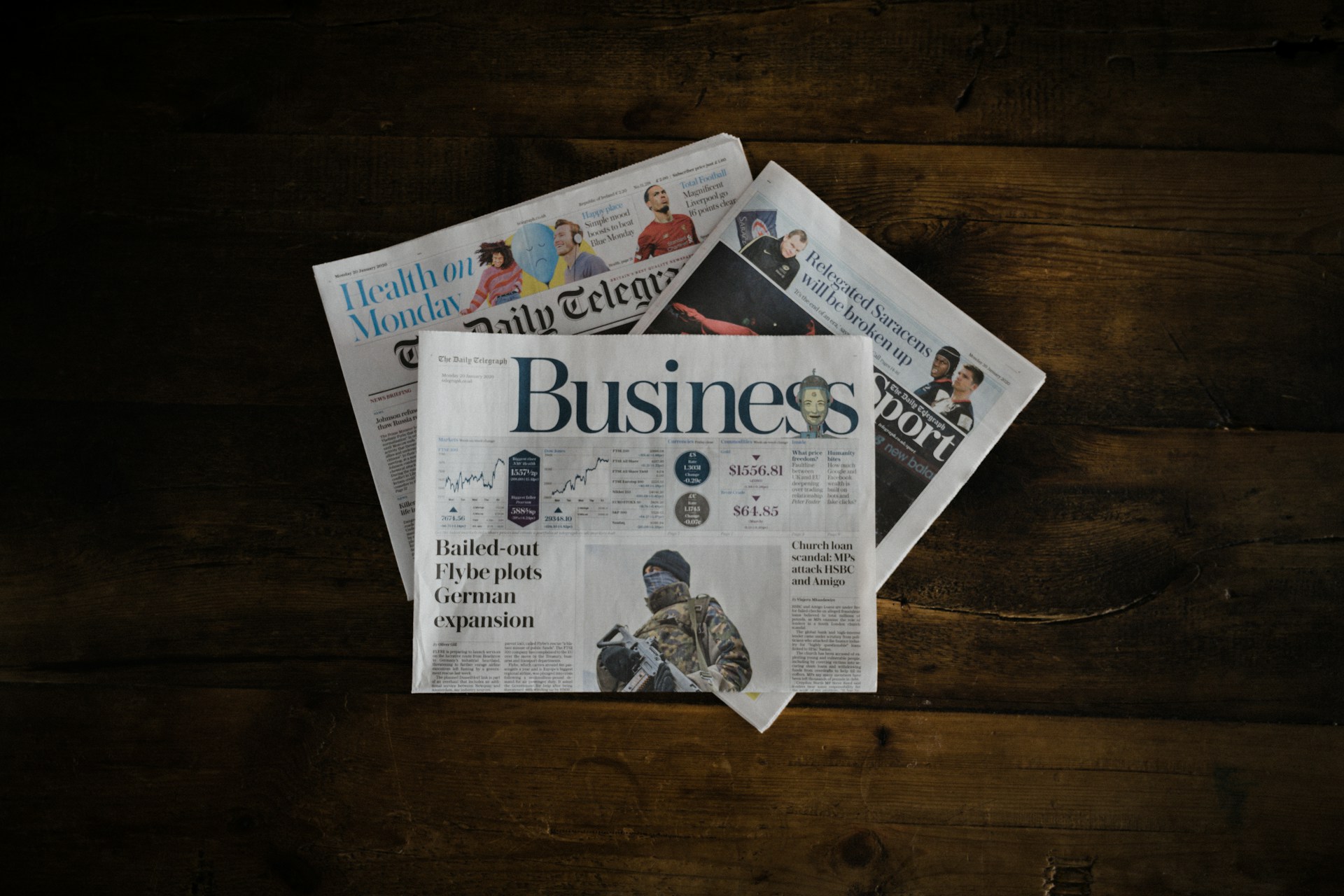 Newspapers on a wooden surface | Source: Unsplash