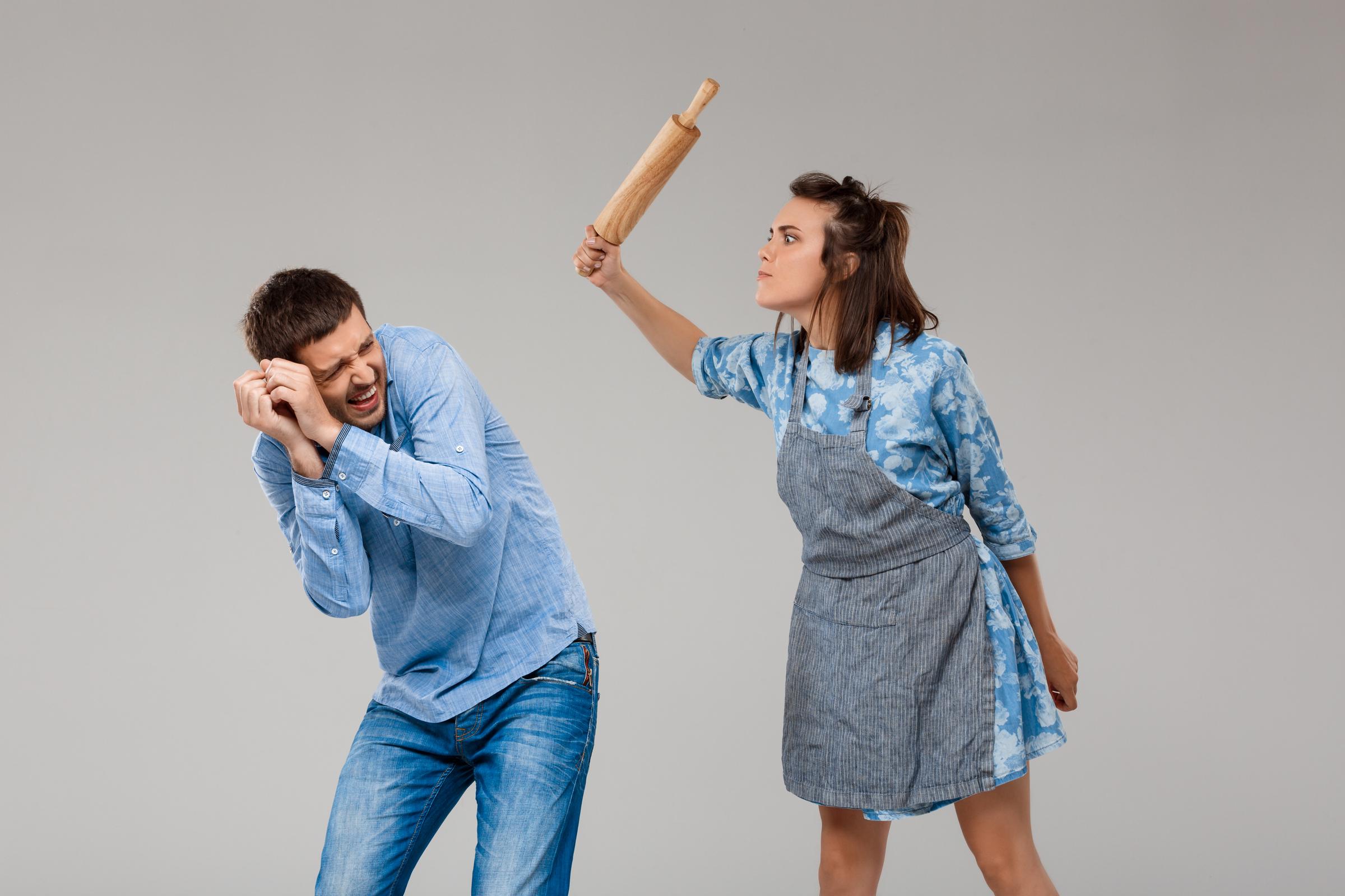 A woman threatening a cowering man | Source: Freepik