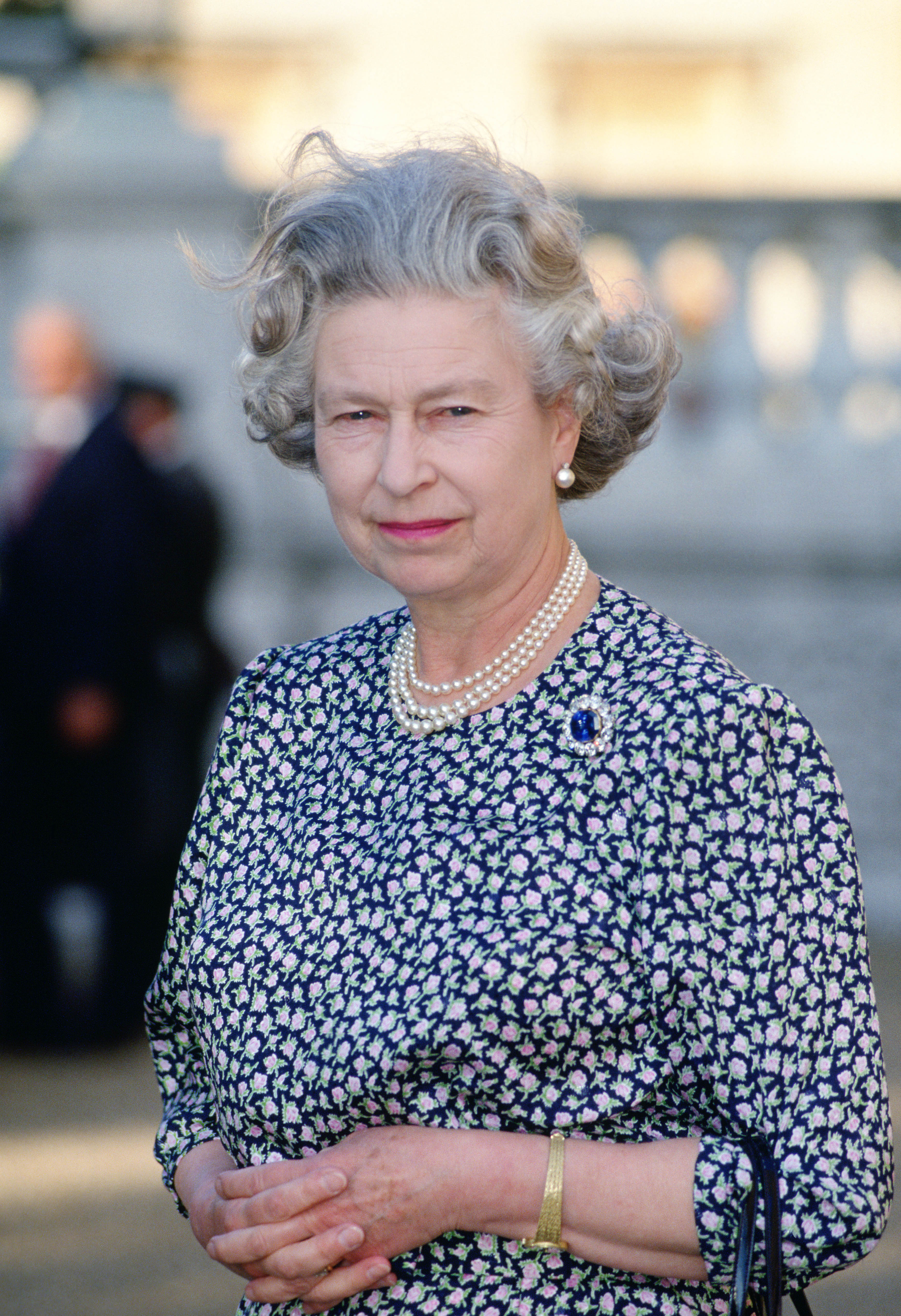 Queen Elizabeth II wearing sapphire and diamond brooch and triple pearl necklace at home in the grounds of Buckingham Palace on July 17, 1991. | Source: Getty Images