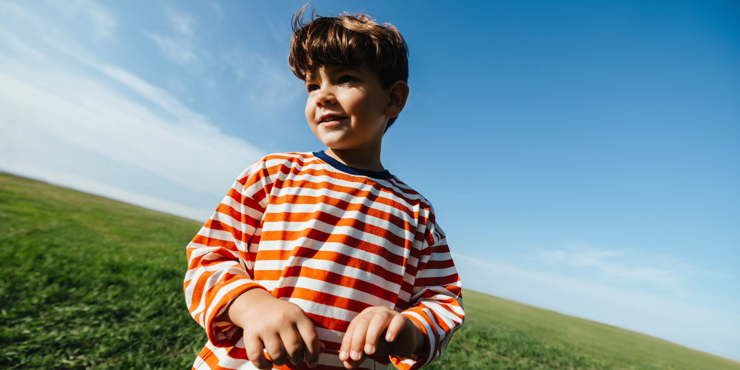 A boy in striped shirt playing outdoors | Source: Getty Images