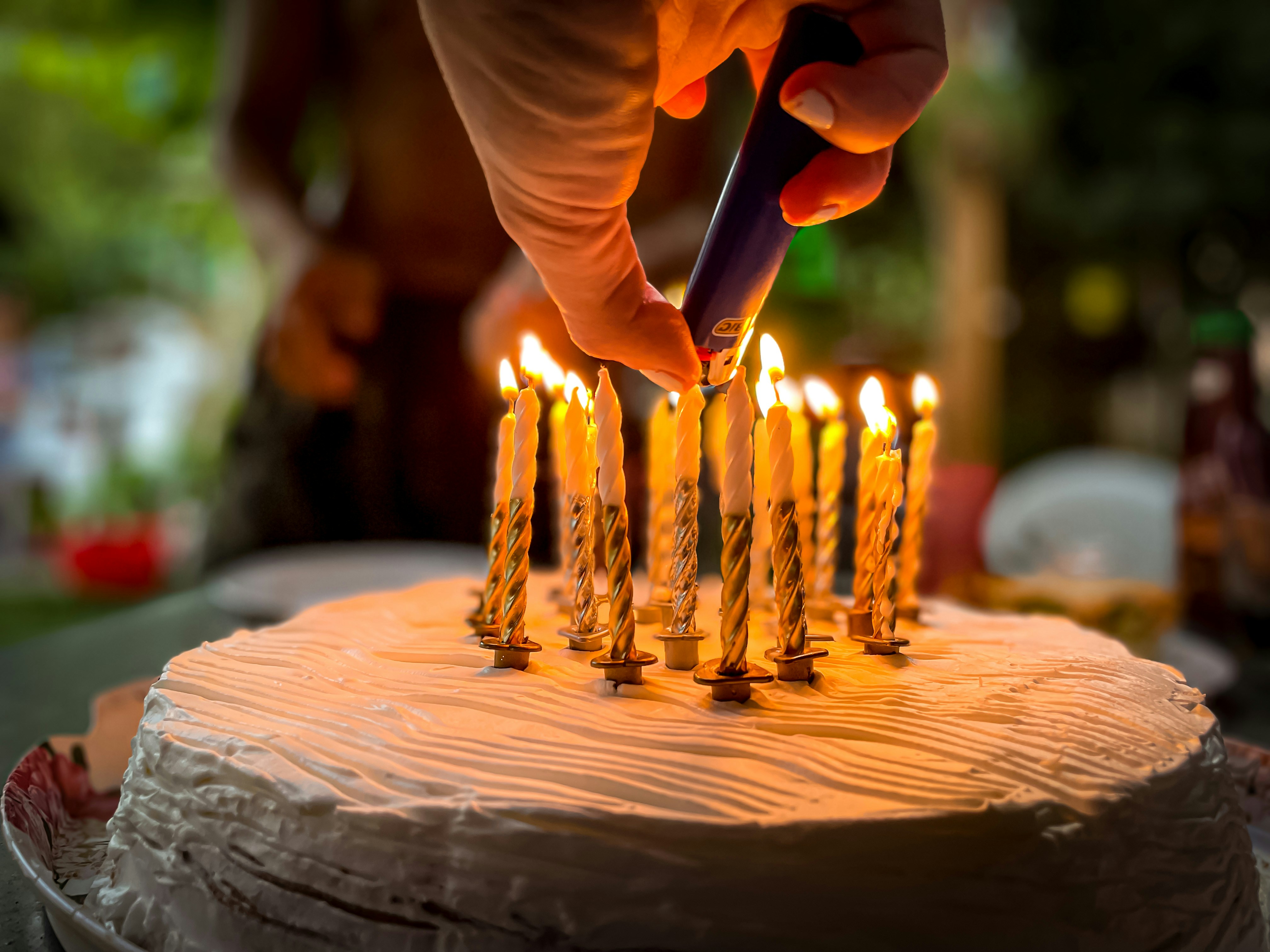 A woman's hand lighting candles on a cake | Source: Unsplash
