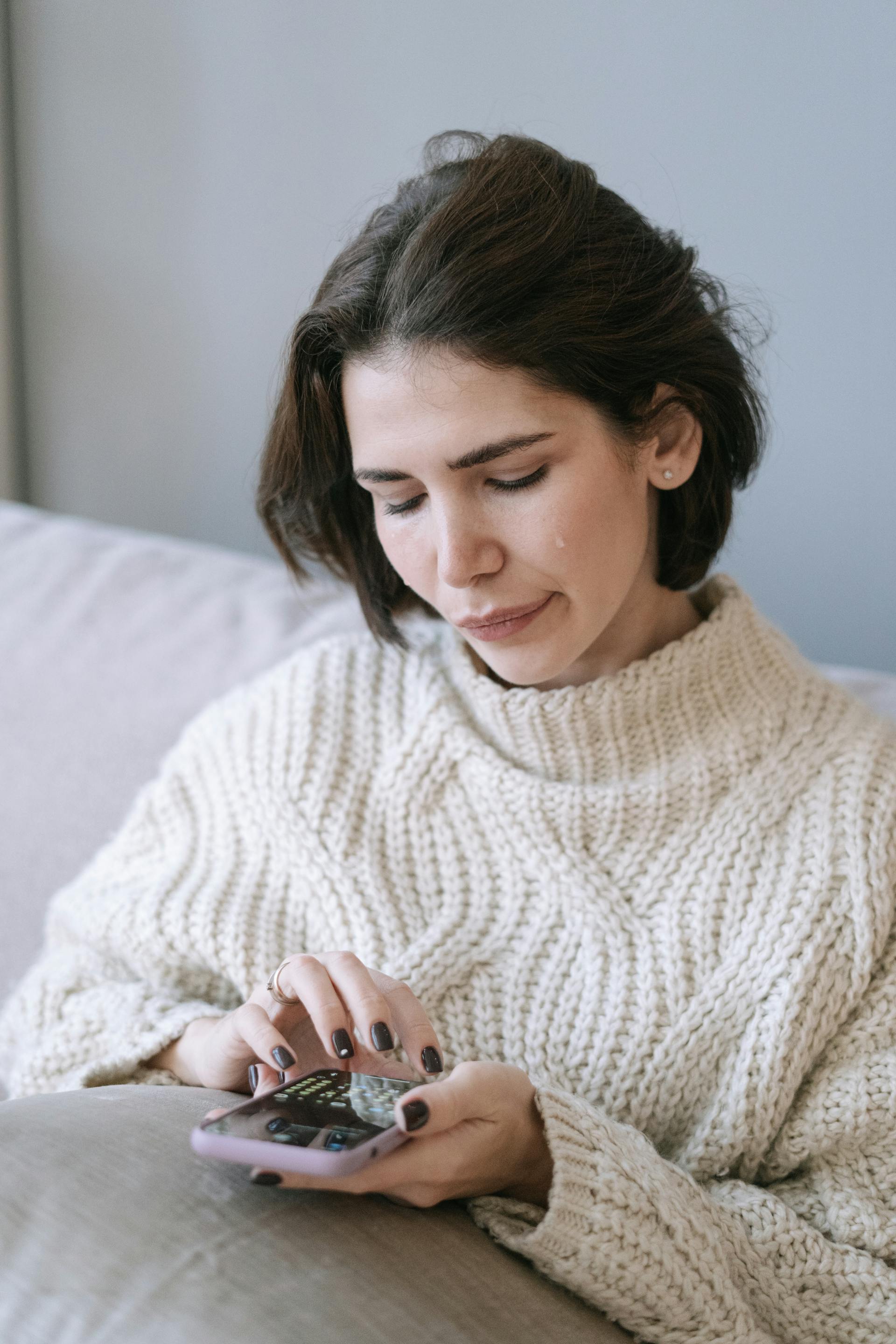 A crying woman holding a cell phone | Source: Pexels