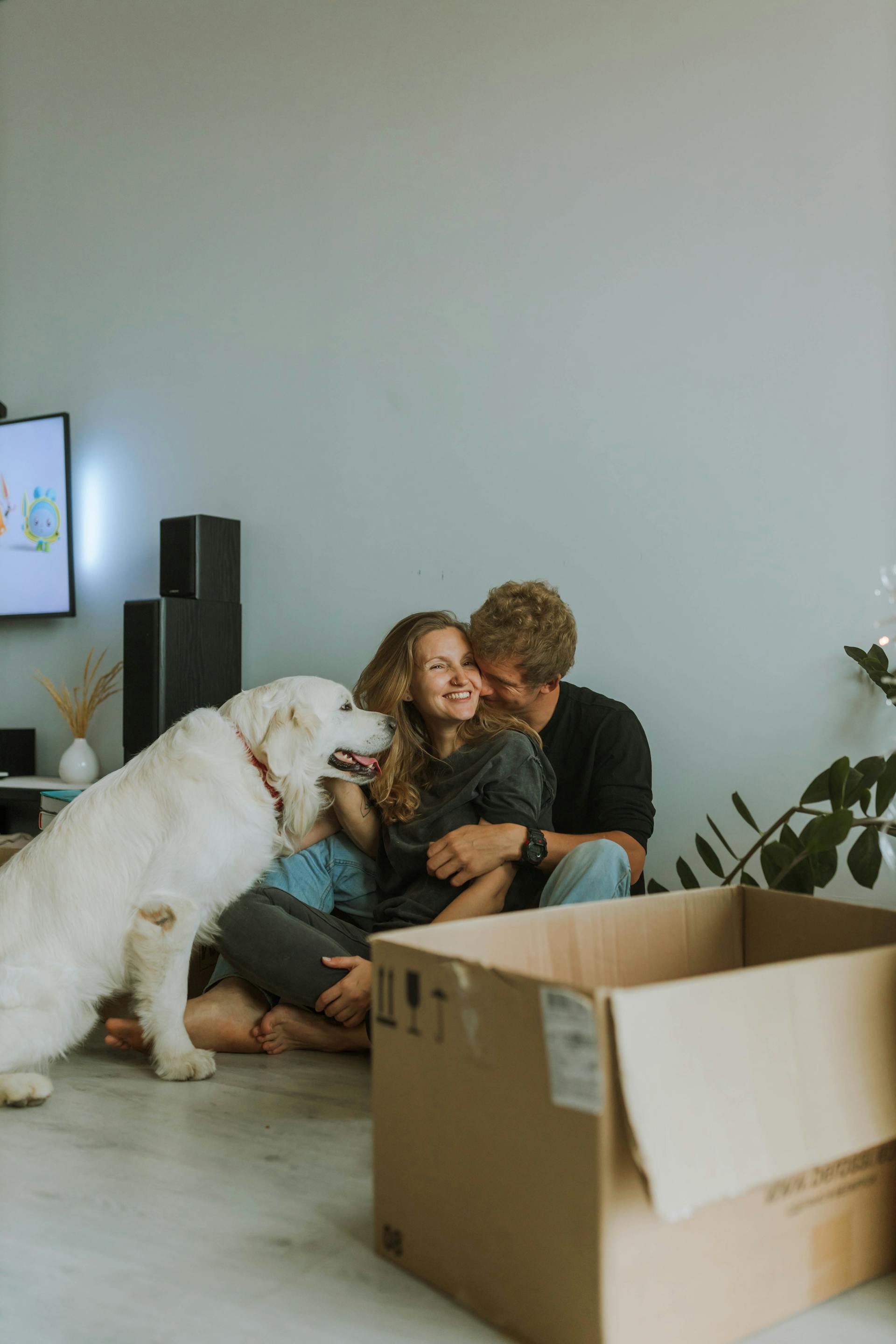 A happy couple cuddling with their dog beside them | Source: Pexels