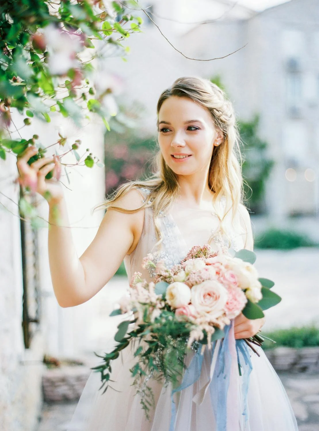 A smiling bride touching flowers | Source: Pexels