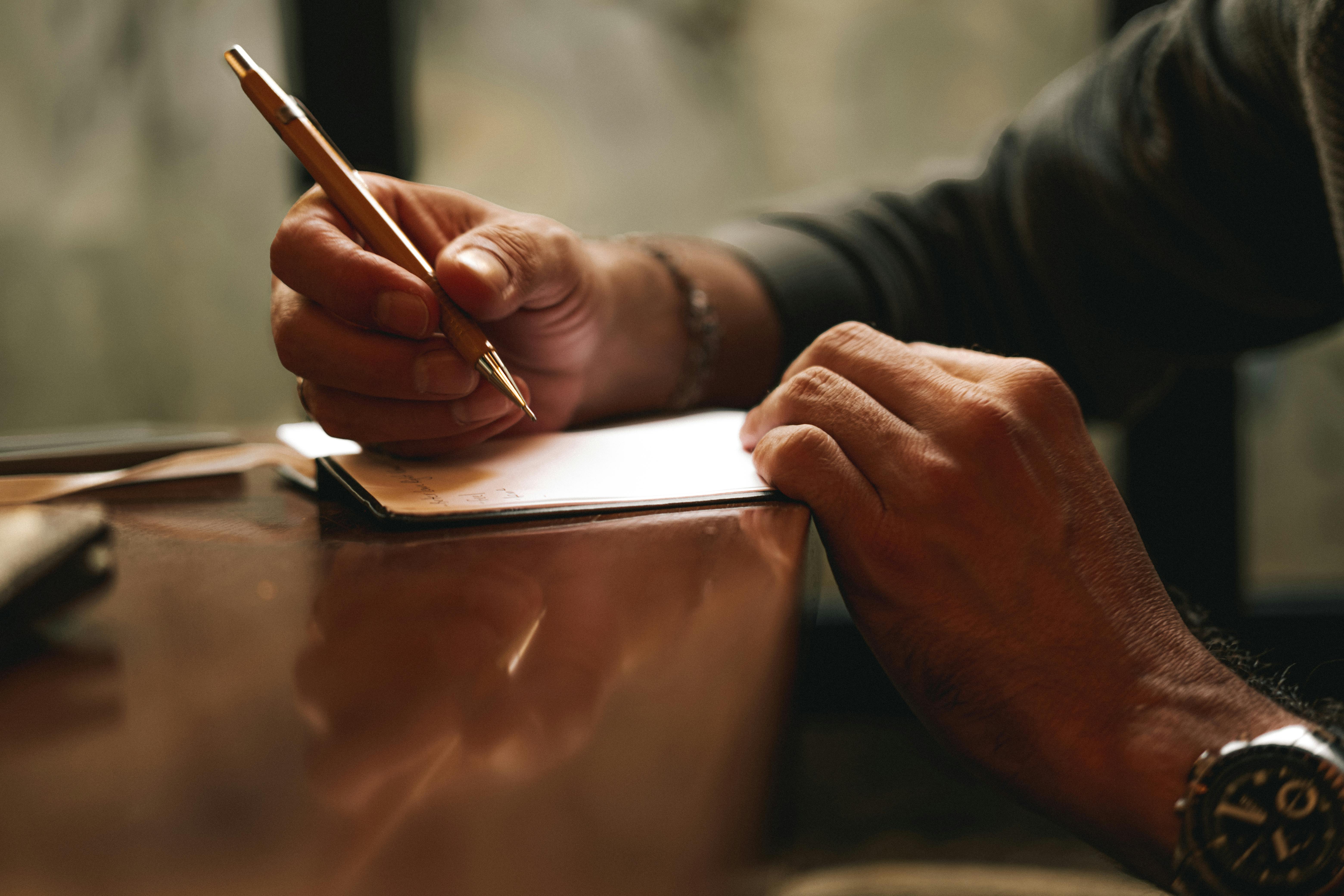 A person writing on a piece of paper | Source: Pexels