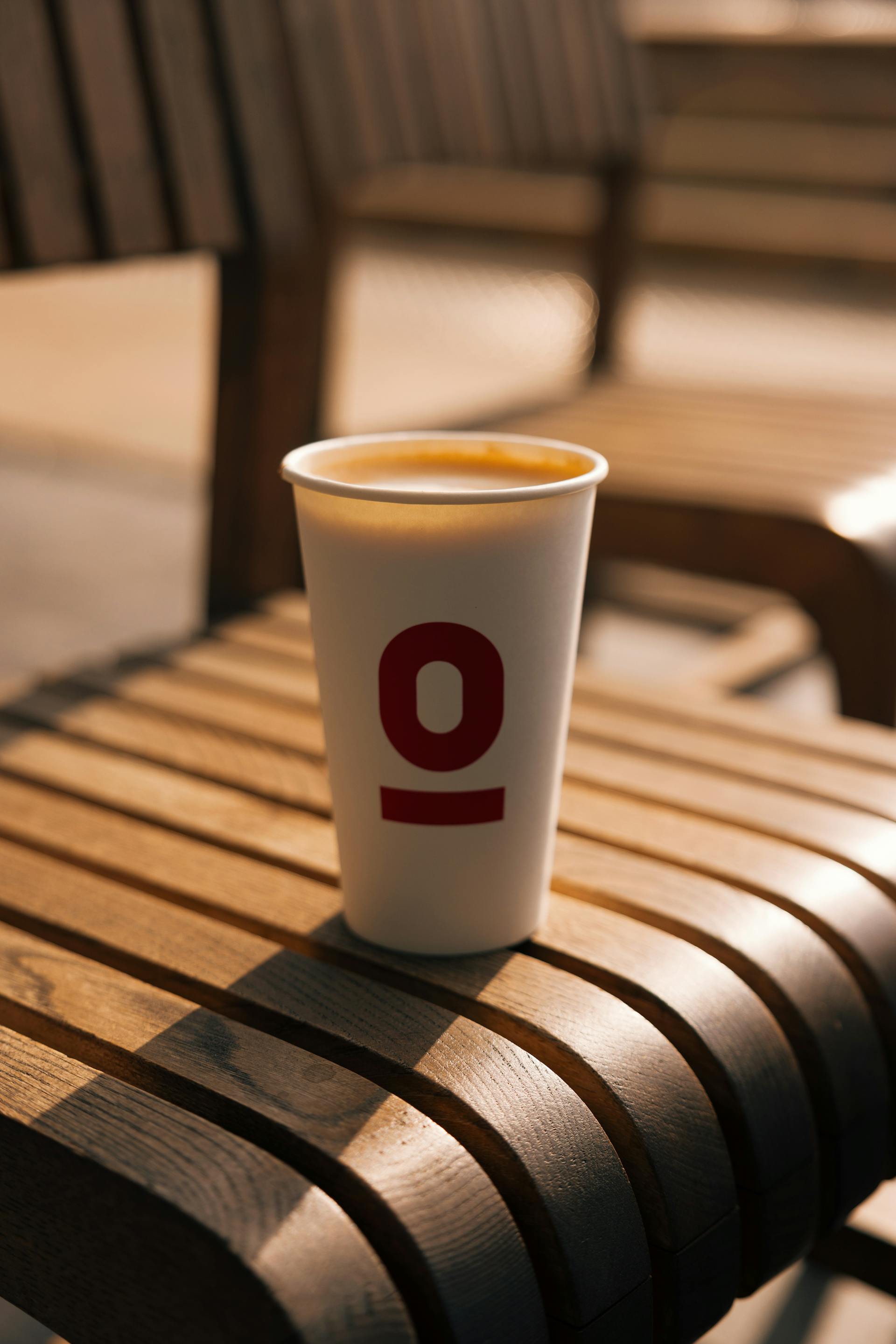 Coffee in a paper cup placed on a wooden chair | Source: Pexels