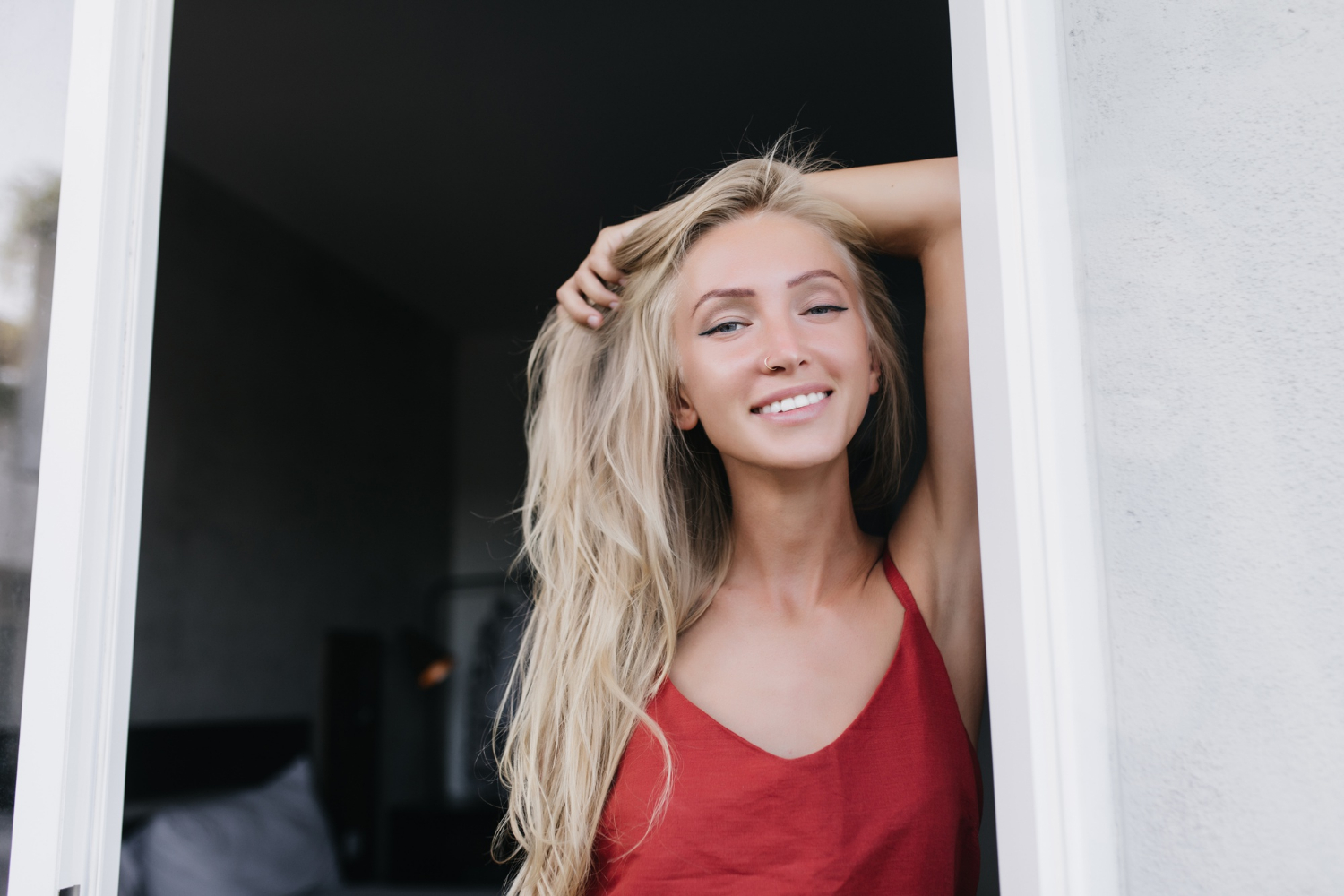 A smiling woman standing at the doorway | Source: Freepik
