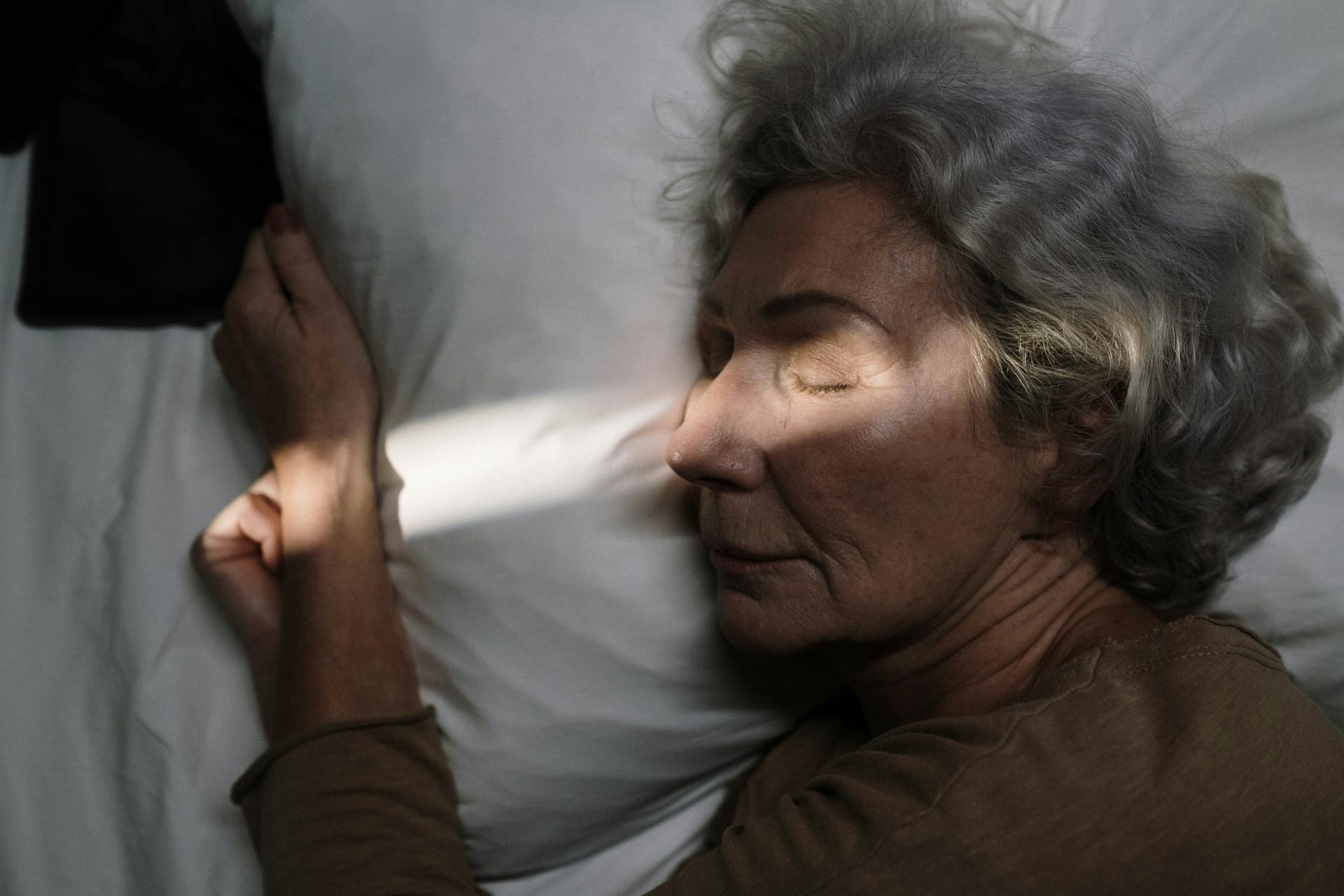 An older woman lying on the bed with her eyes closed | Source: Pexels