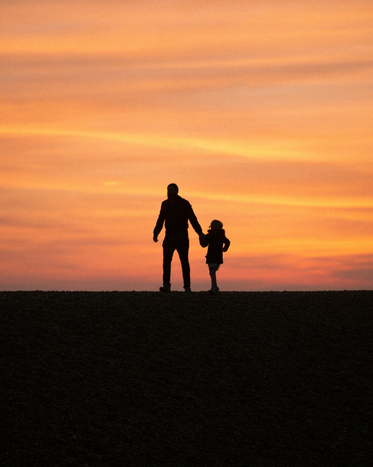 Silhouette of a man walking with his little daughter | Source: Pexels