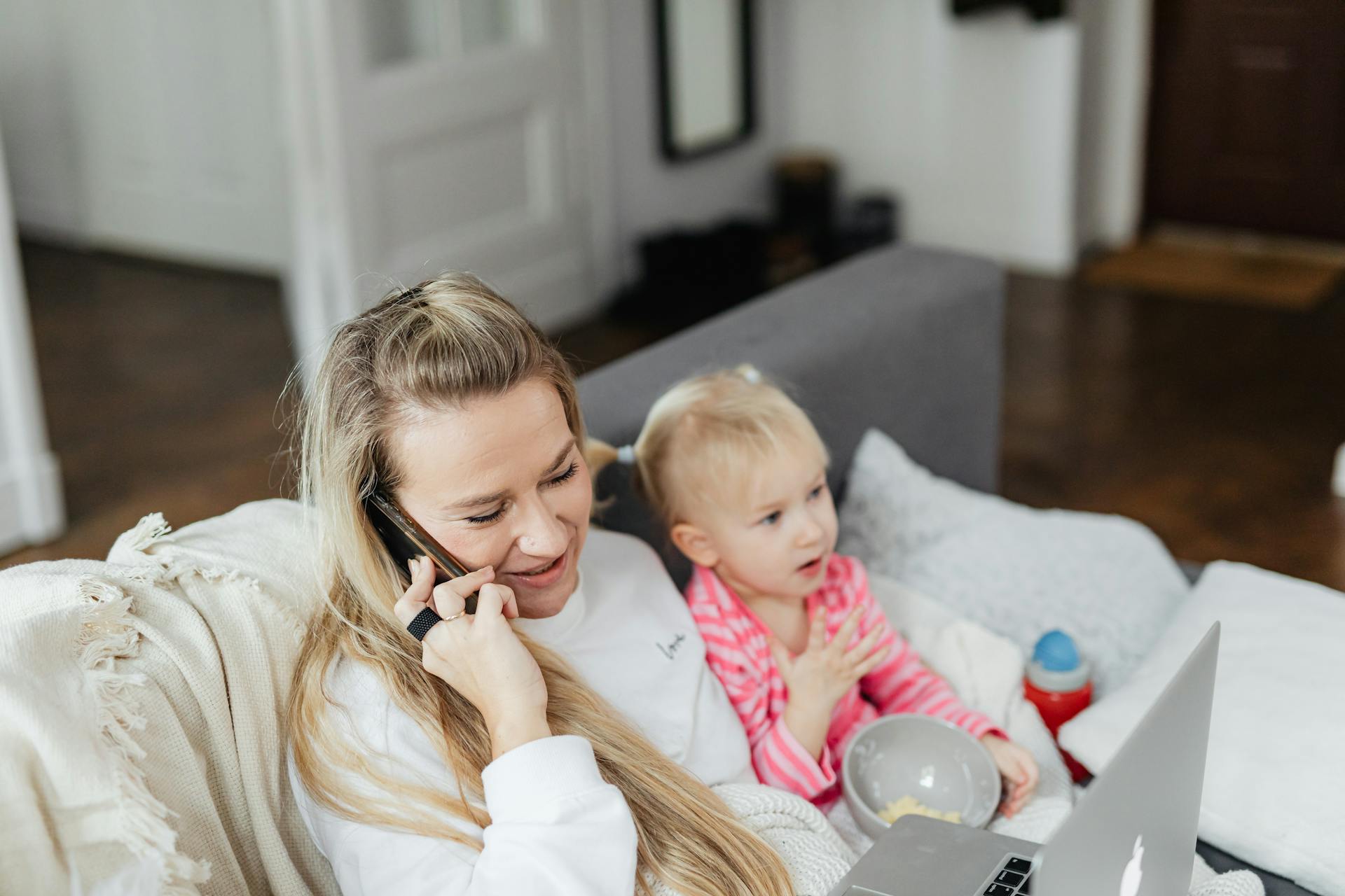 A woman talking on her phone while caring for her daughter | Source: Pexels