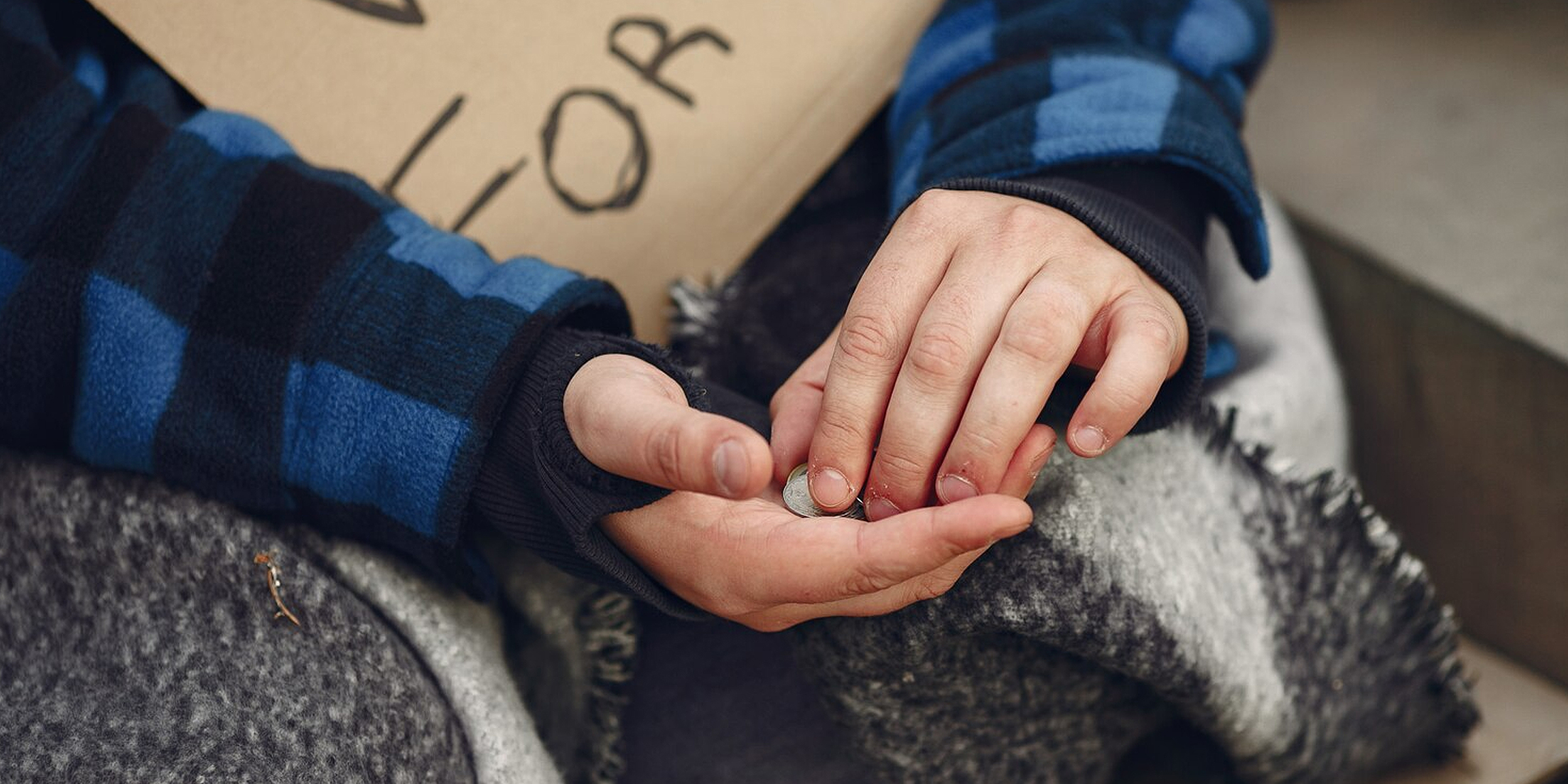 A beggar counting coins in her hands | Source: Freepik