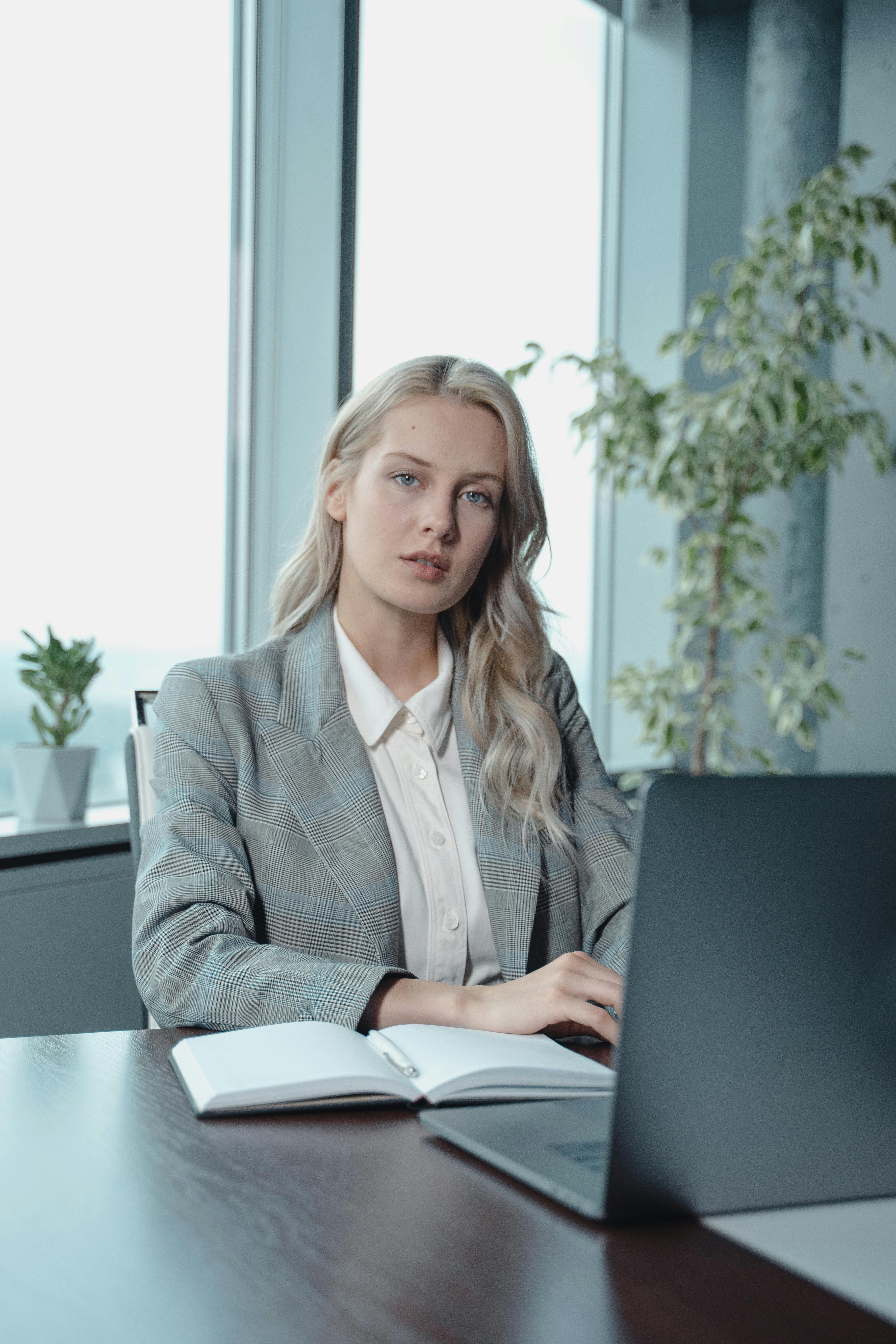 Woman in gray blazer sitting by the table with a laptop | Source: Pexels