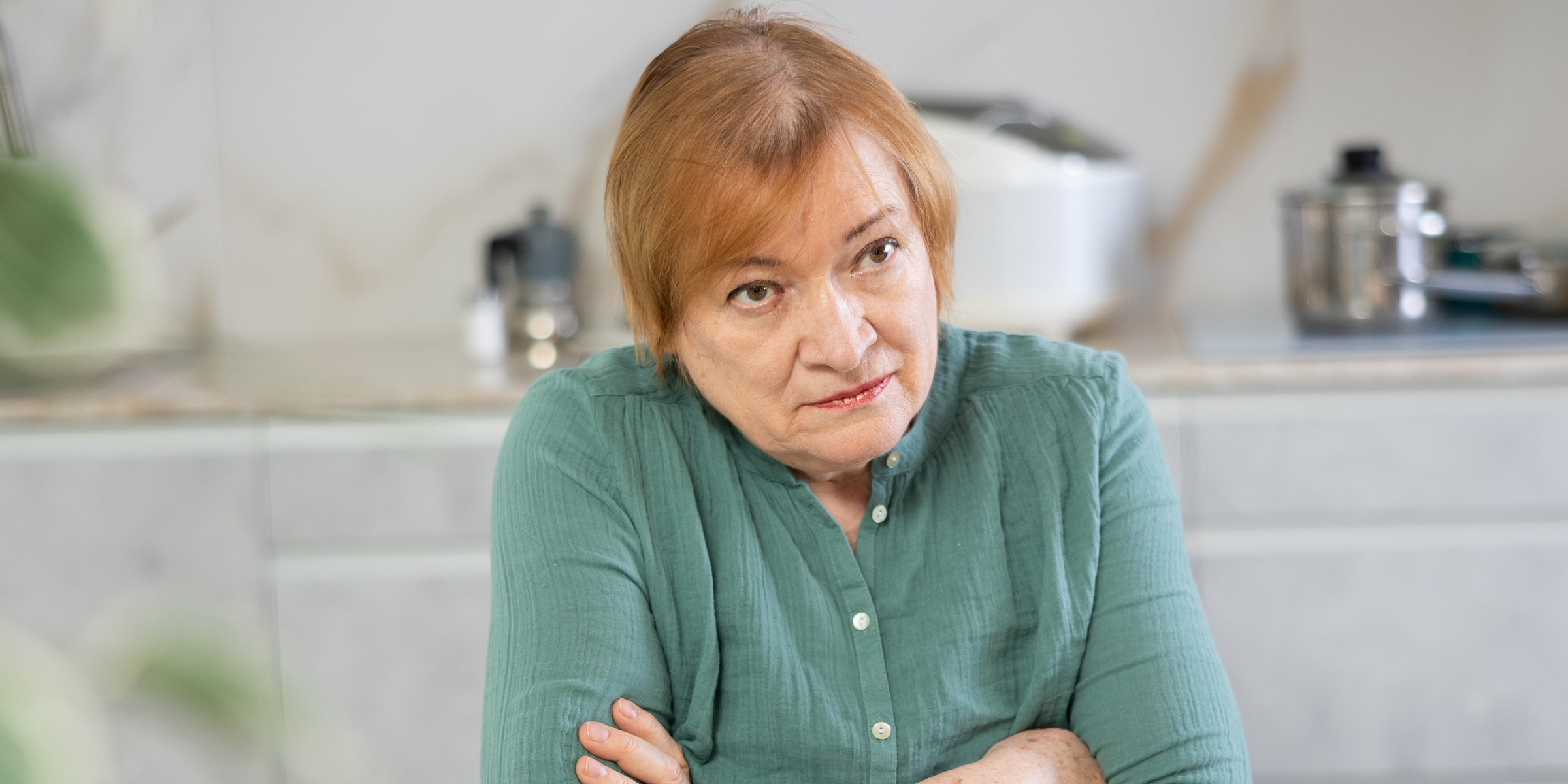 An unimpressed older woman sitting with her arms crossed | Source: Shutterstock