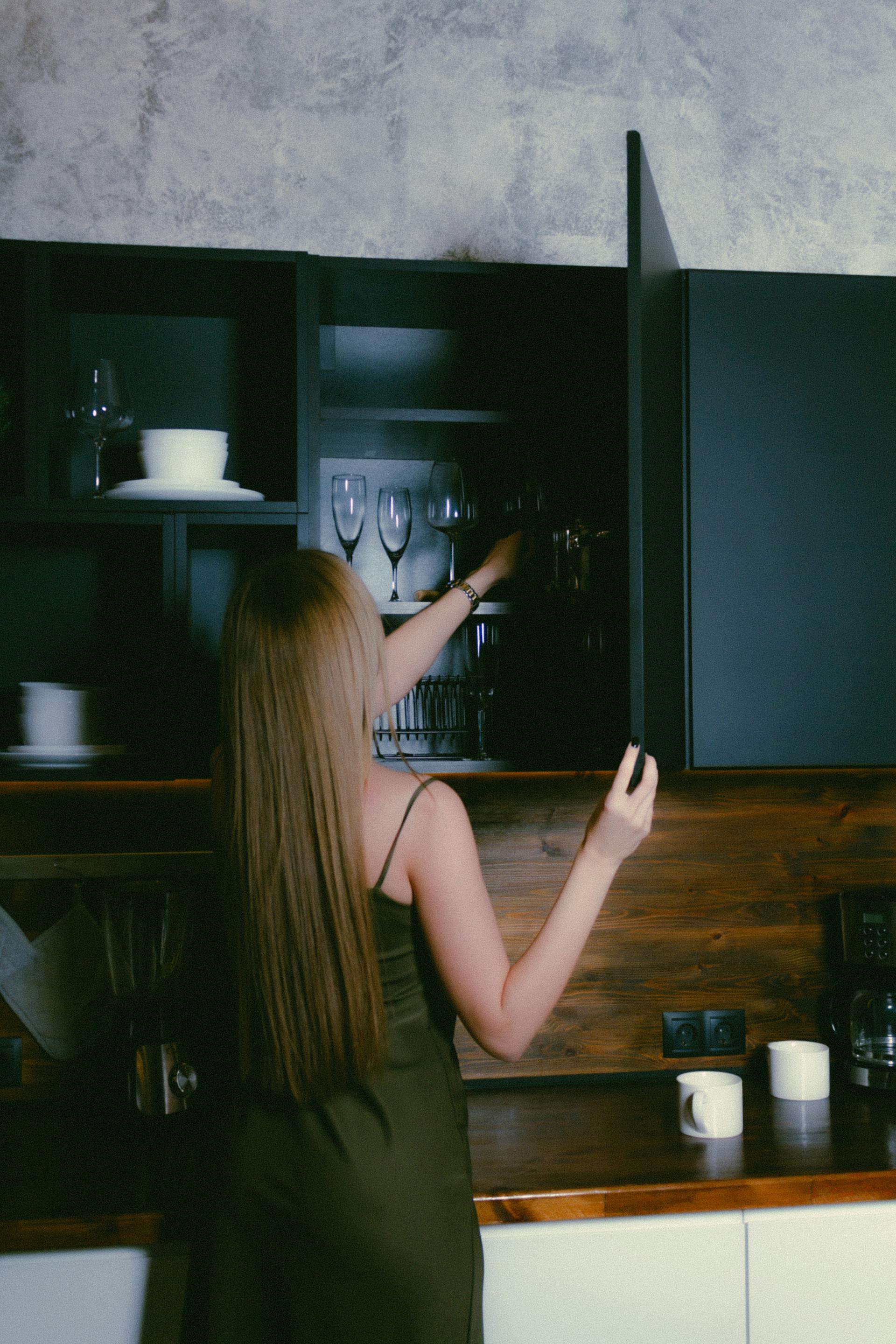 A woman packing items into kitchen cupboards | Source: Pexels